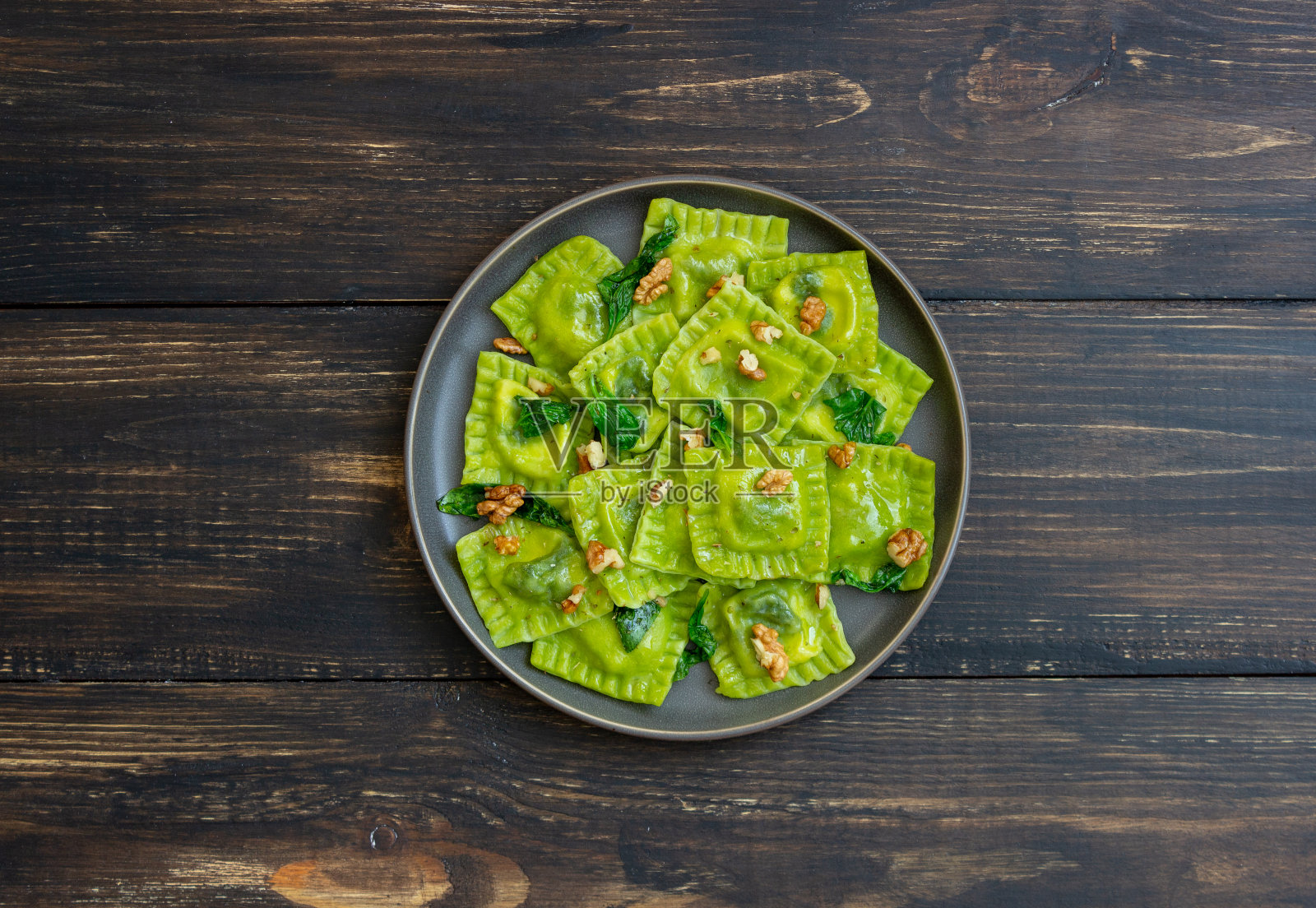 意大利乳清干酪、菠菜和坚果的绿色馄饨。健康饮食。素食。意大利菜。照片摄影图片