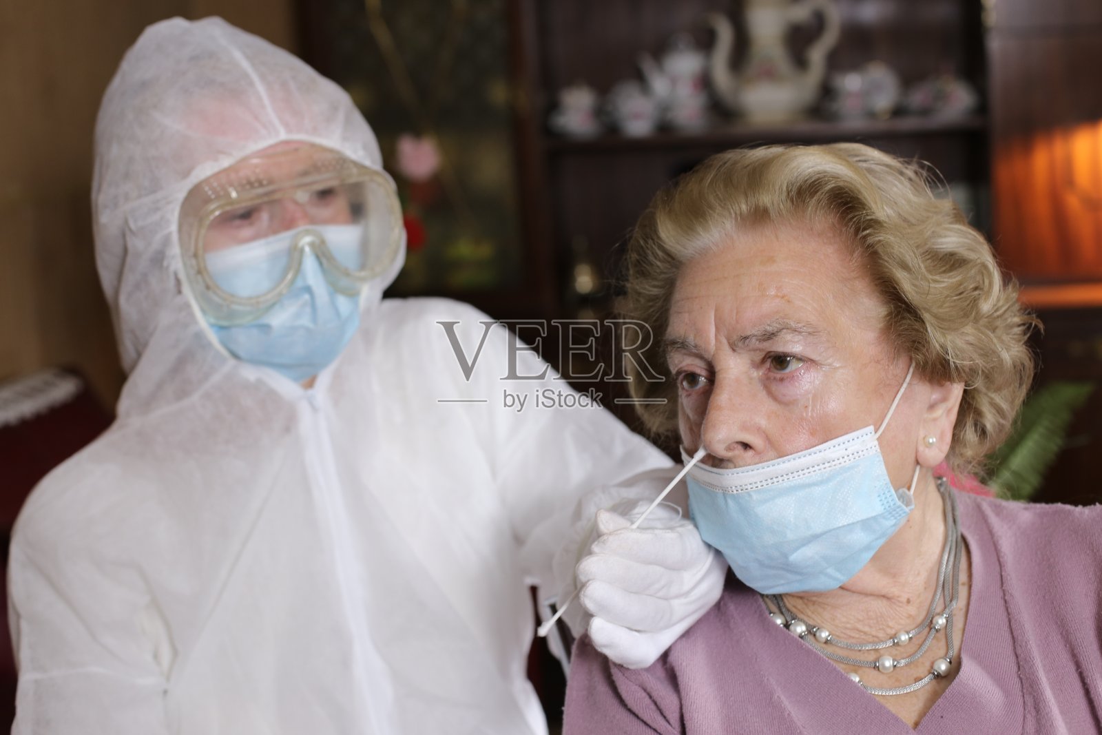 年长妇女在家接受聚合酶链反应测试由佩戴防护装备的护士完成照片摄影图片