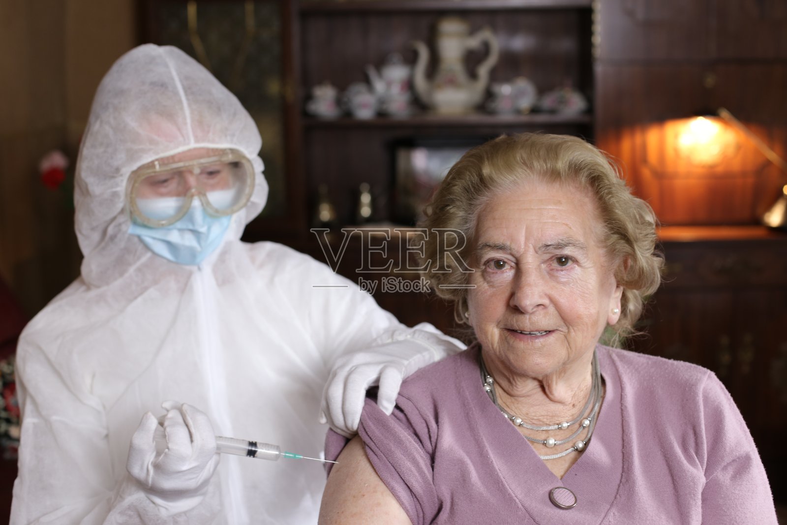 护士穿着防护服给一位快乐的老年妇女接种疫苗照片摄影图片