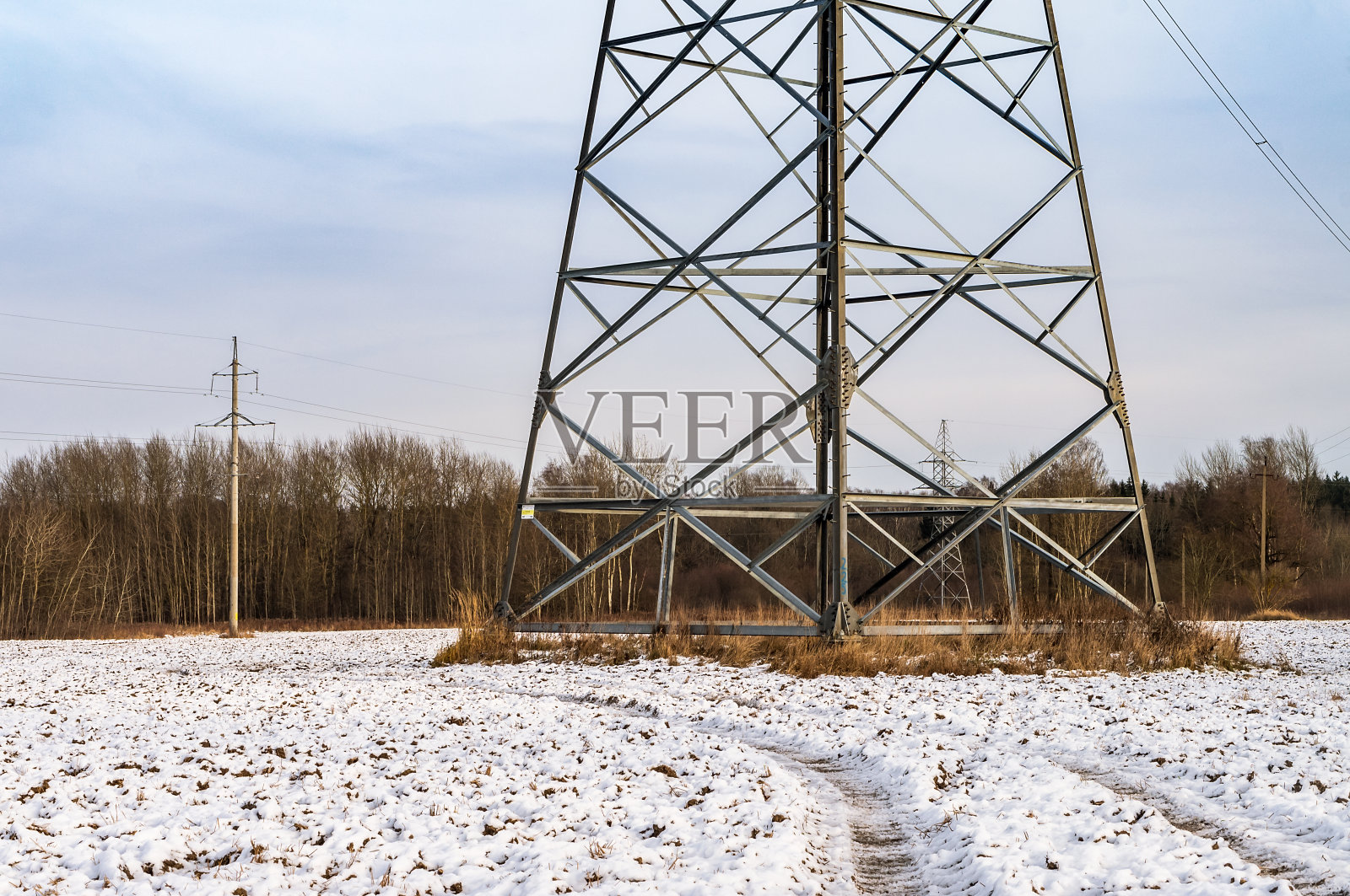野外的电线。雪中的工业塔。冬天田地里的输电线。照片摄影图片