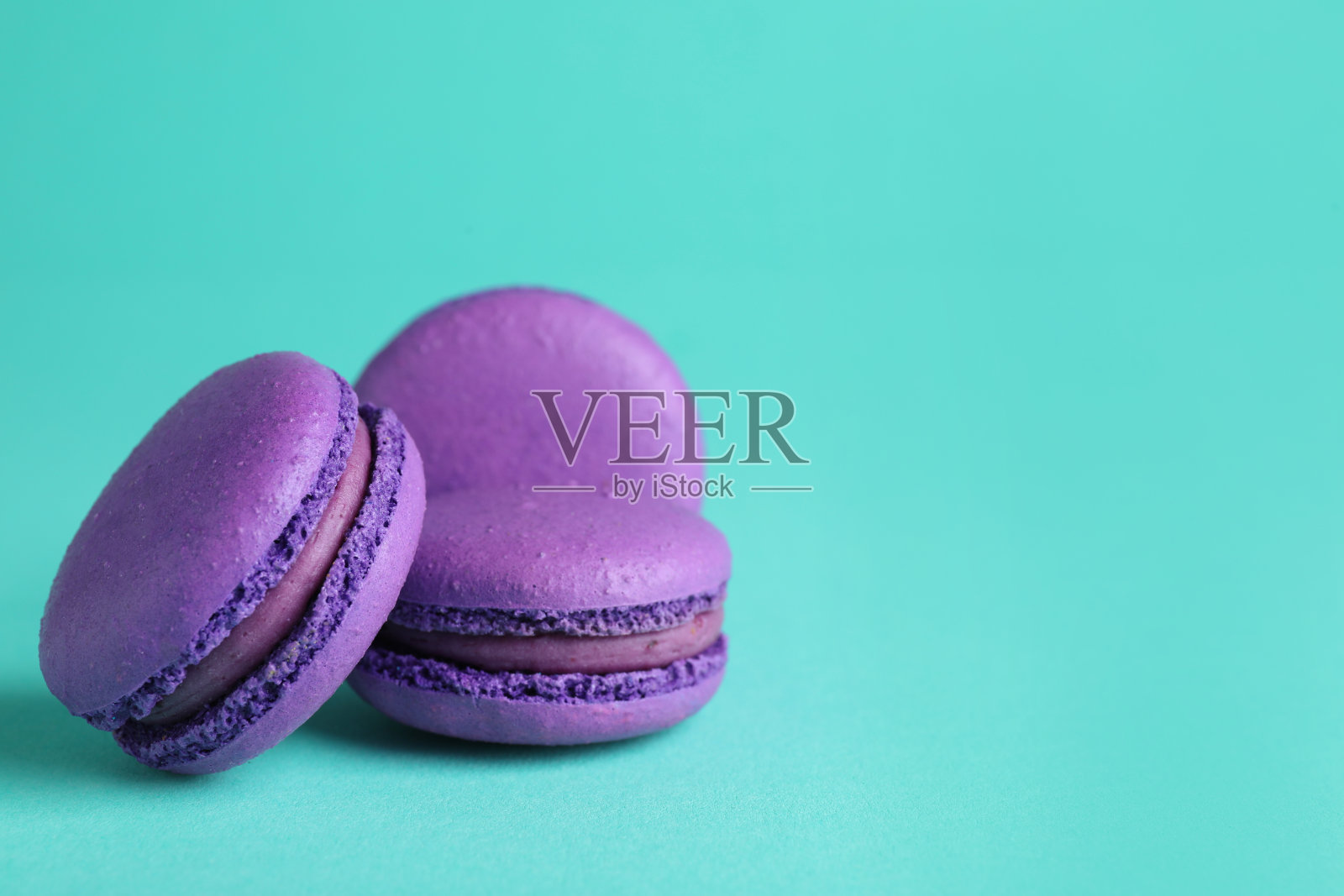 美味的紫色马卡龙在绿松石的背景。空间的文本照片摄影图片