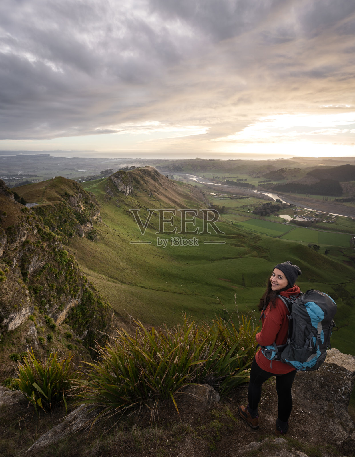 年轻女子背着背包在山顶摆姿势。垂直摄影照片摄影图片