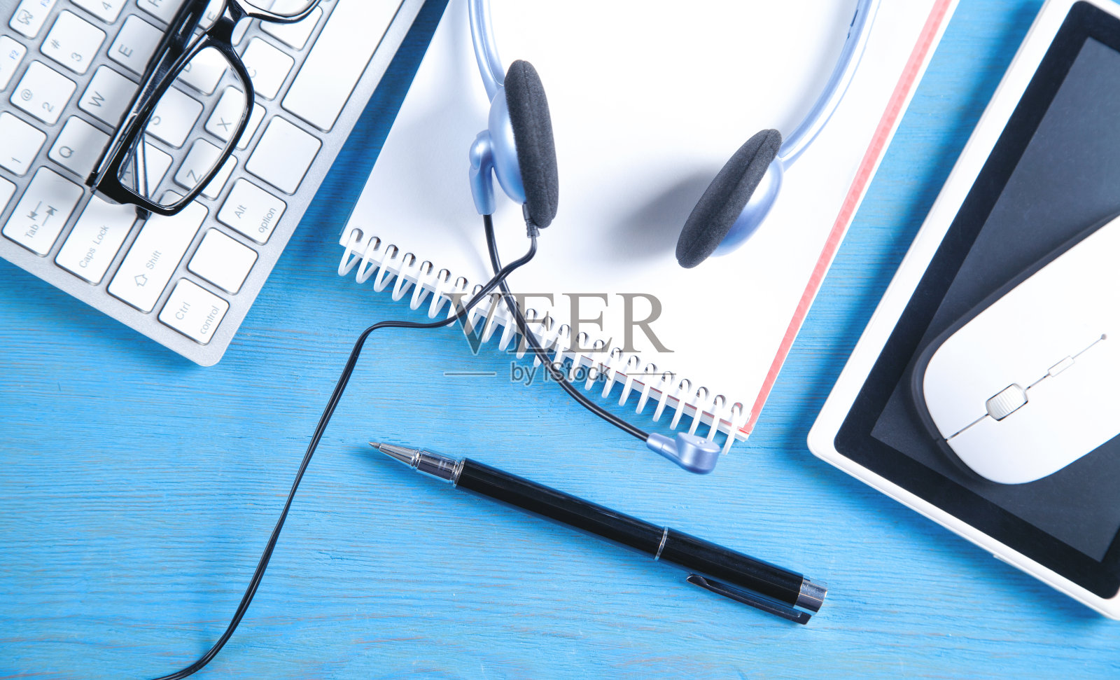 蓝色背景上的客户服务耳机、电脑键盘和业务对象。照片摄影图片