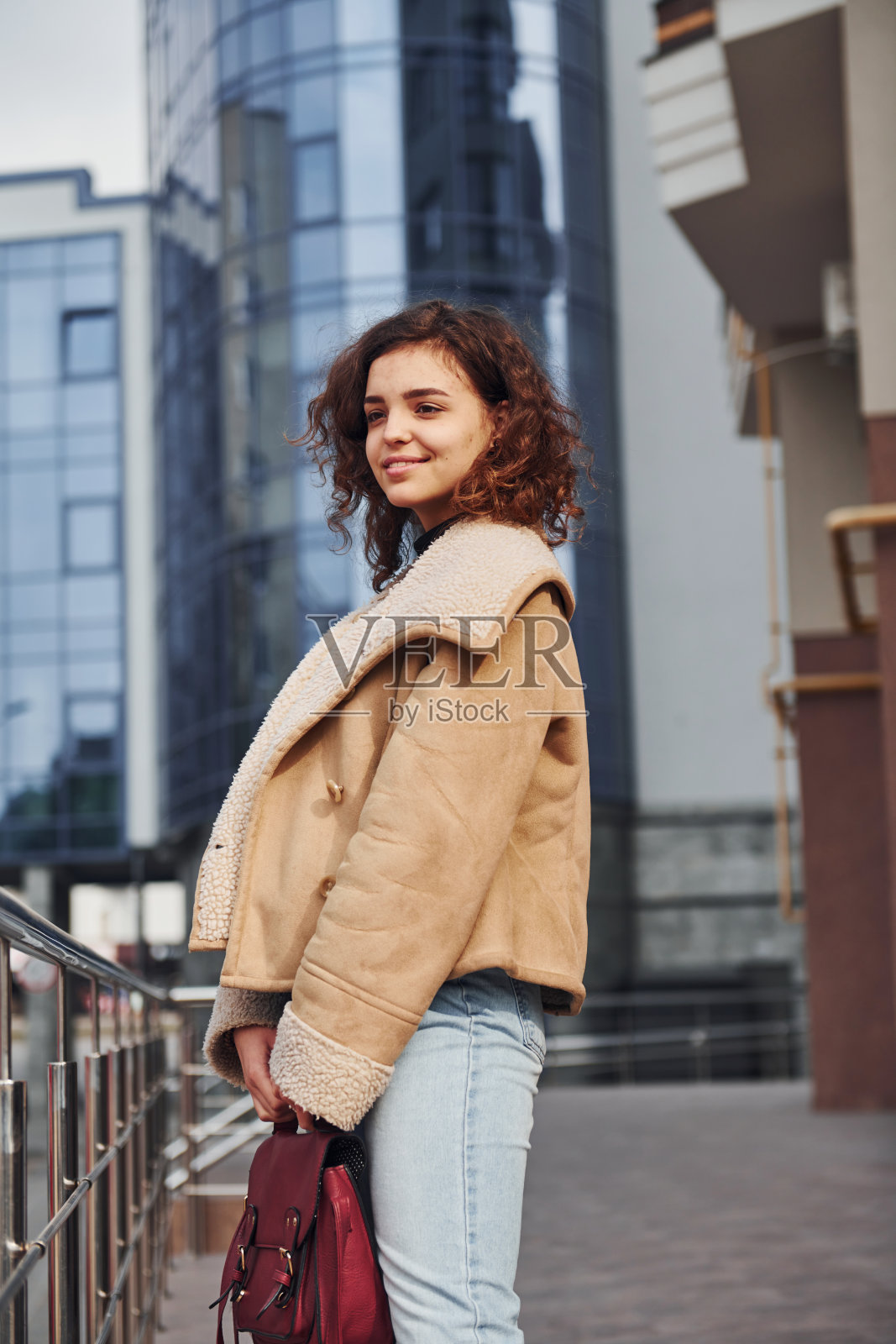 一个年轻的女孩在城市里的商业大楼附近散步照片摄影图片