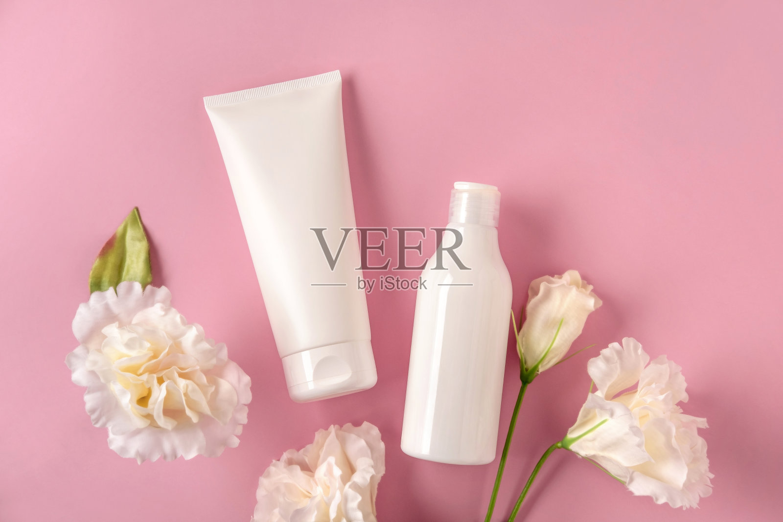 两个白色模拟瓶的品牌与白花。粉色背景上的化妆模型。照片摄影图片