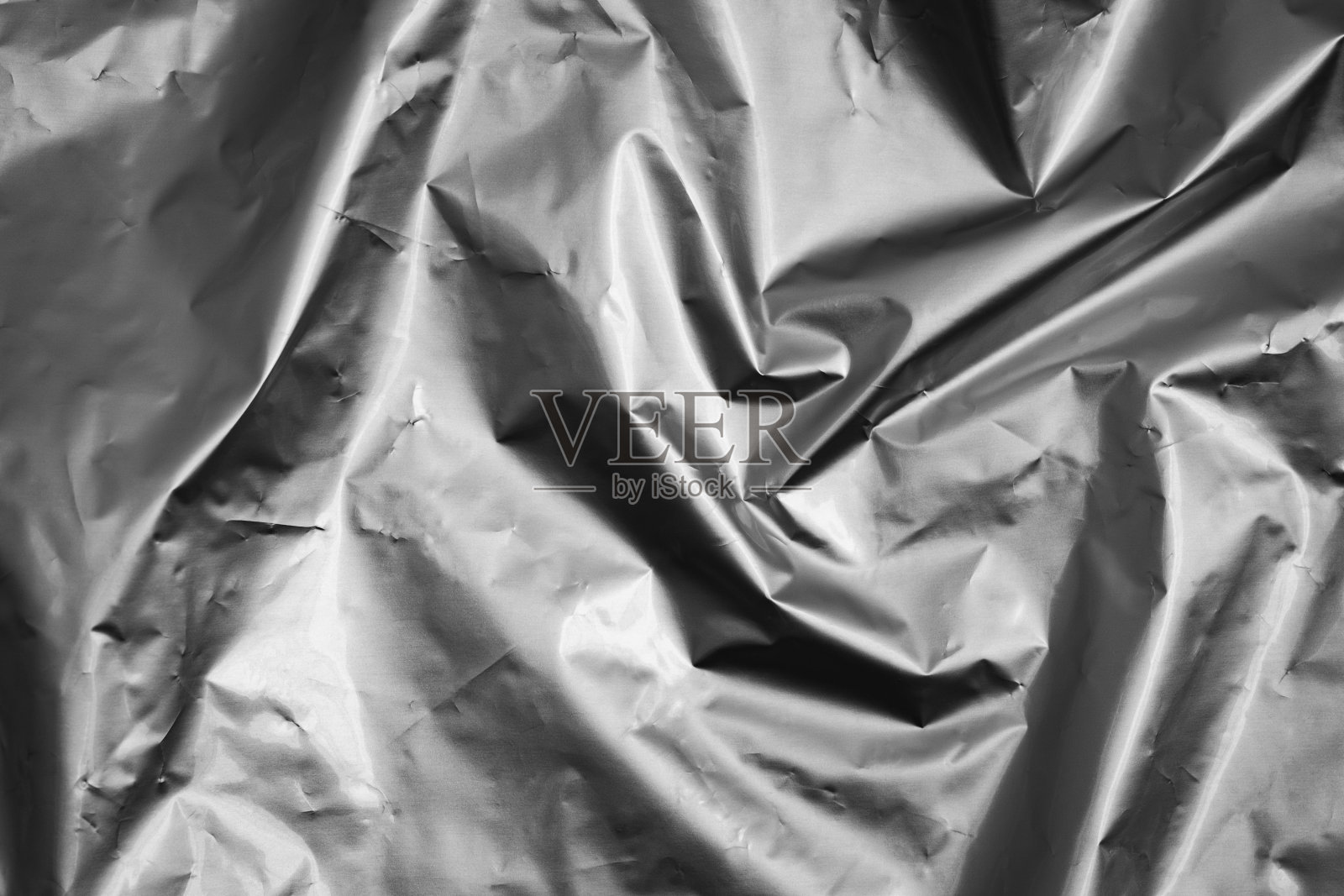 黑色和白色光泽褶皱的箔纹理，抽象的形状为背景。照片摄影图片