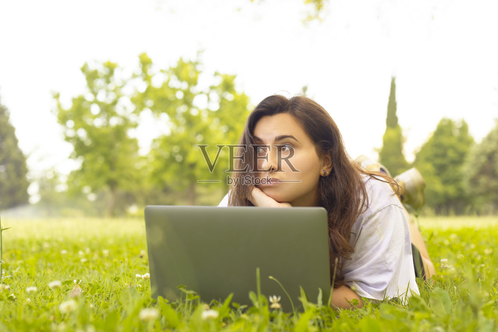 年轻的大学生在课堂上遇到问题时，把目光从她的手放在下巴上，开始思考。照片摄影图片