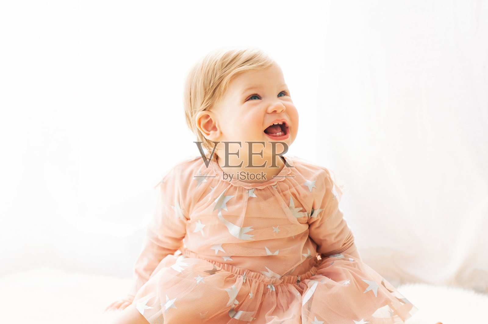 轻软的肖像可爱的蹒跚学步1岁的小女孩，穿着粉红色的裙子，坐在窗户旁边照片摄影图片