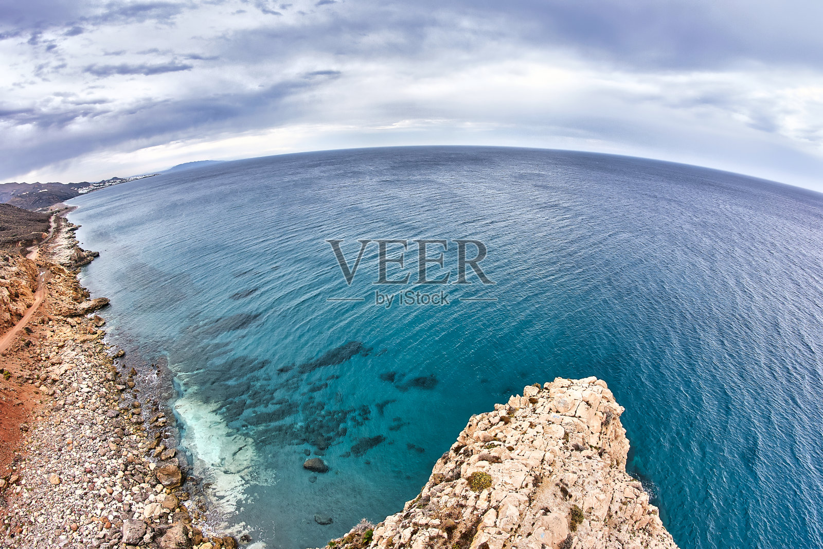 西班牙阿尔梅里亚El Sombrerico海滩附近的Torre del Pirulico——在西班牙阿尔梅里亚的Sombrerico海滩上，一块巨大的尖顶状岩石被称为tip del Sombrerico——阳光灿烂的日子照片摄影图片