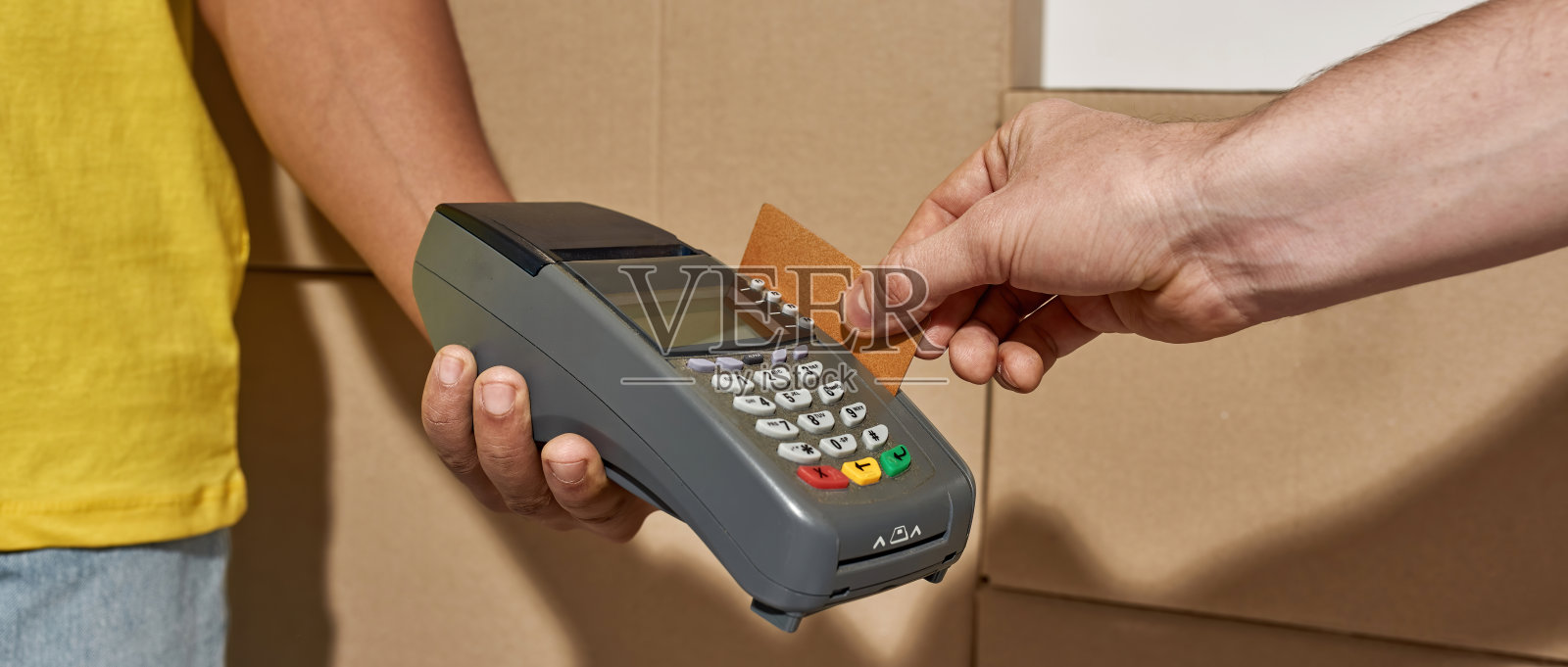 近距离拍摄的手，送货员持有终端客户支付包裹收到快递与信用卡。背景是纸板箱照片摄影图片