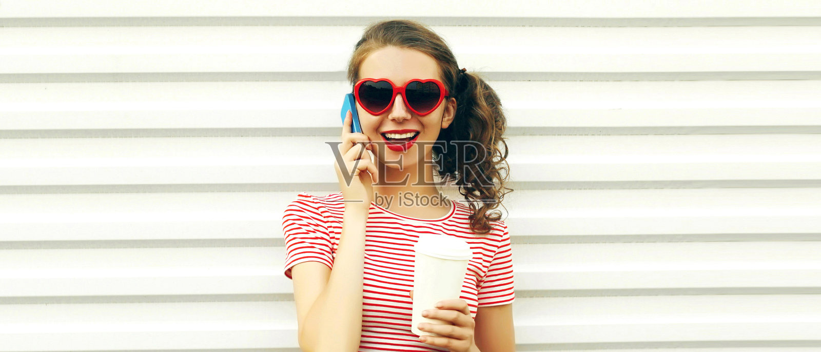 肖像特写的快乐大笑的年轻女子打电话与咖啡杯在白色的背景照片摄影图片