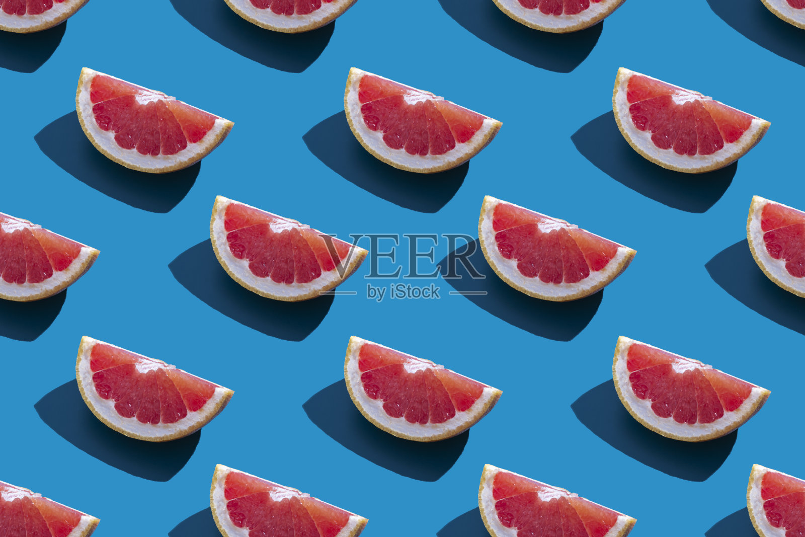 无缝图案的橙色柚子与阴影在一个蓝色的背景。简约时尚的暑假概念。健康的饮食生活方式。照片摄影图片