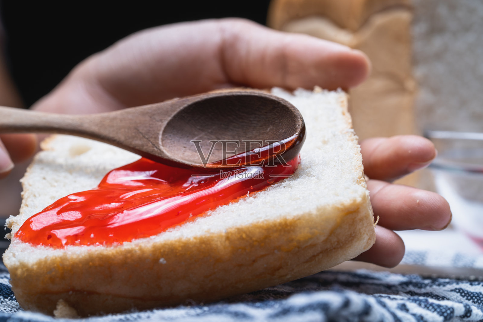 一个女孩正在把草莓酱涂在吐司上。照片摄影图片