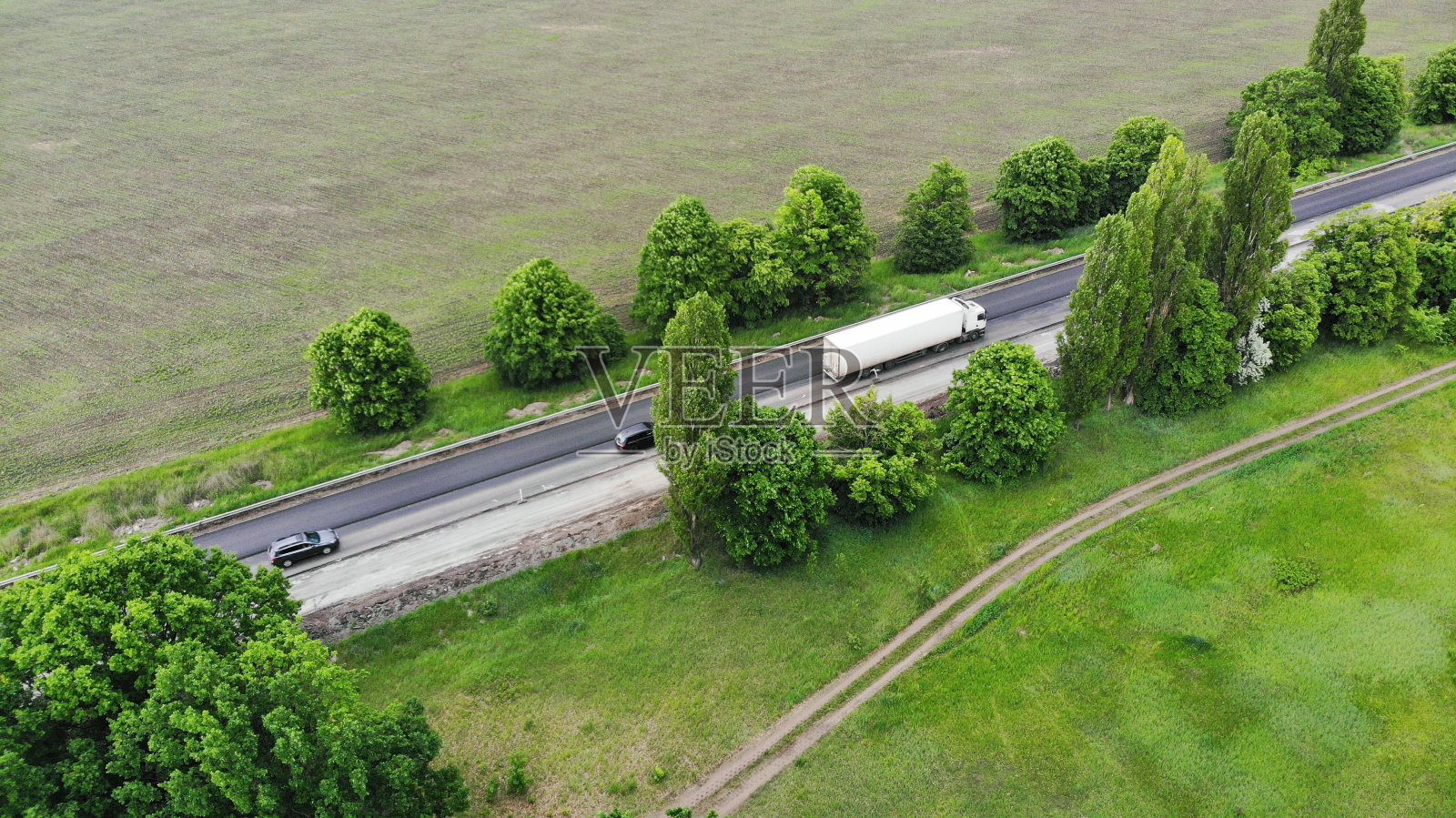 天线。运输物流的背景。卡车在田地间的高速公路上行驶。从无人机上俯瞰。照片摄影图片