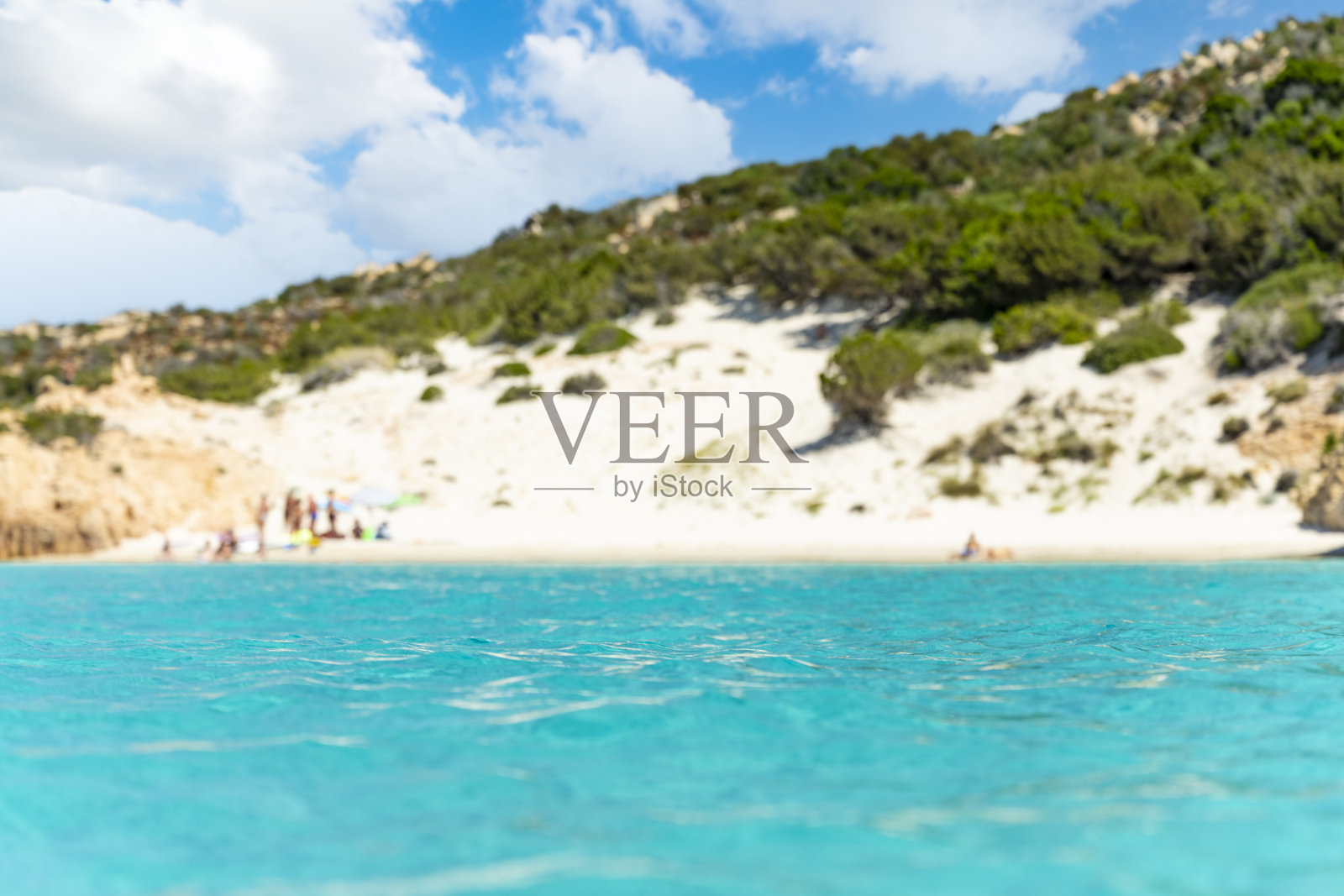 (选择性聚焦)背景中散焦的白色沙滩，前景中沐浴着美丽的绿松石海。意大利撒丁岛马达莱纳群岛的斯帕吉岛。照片摄影图片