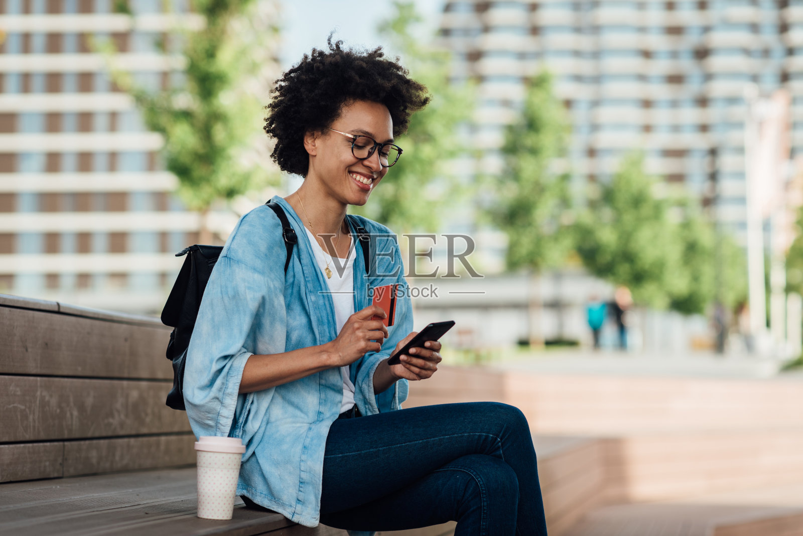 非洲裔美国年轻女子在网上购物和享受在码头照片摄影图片