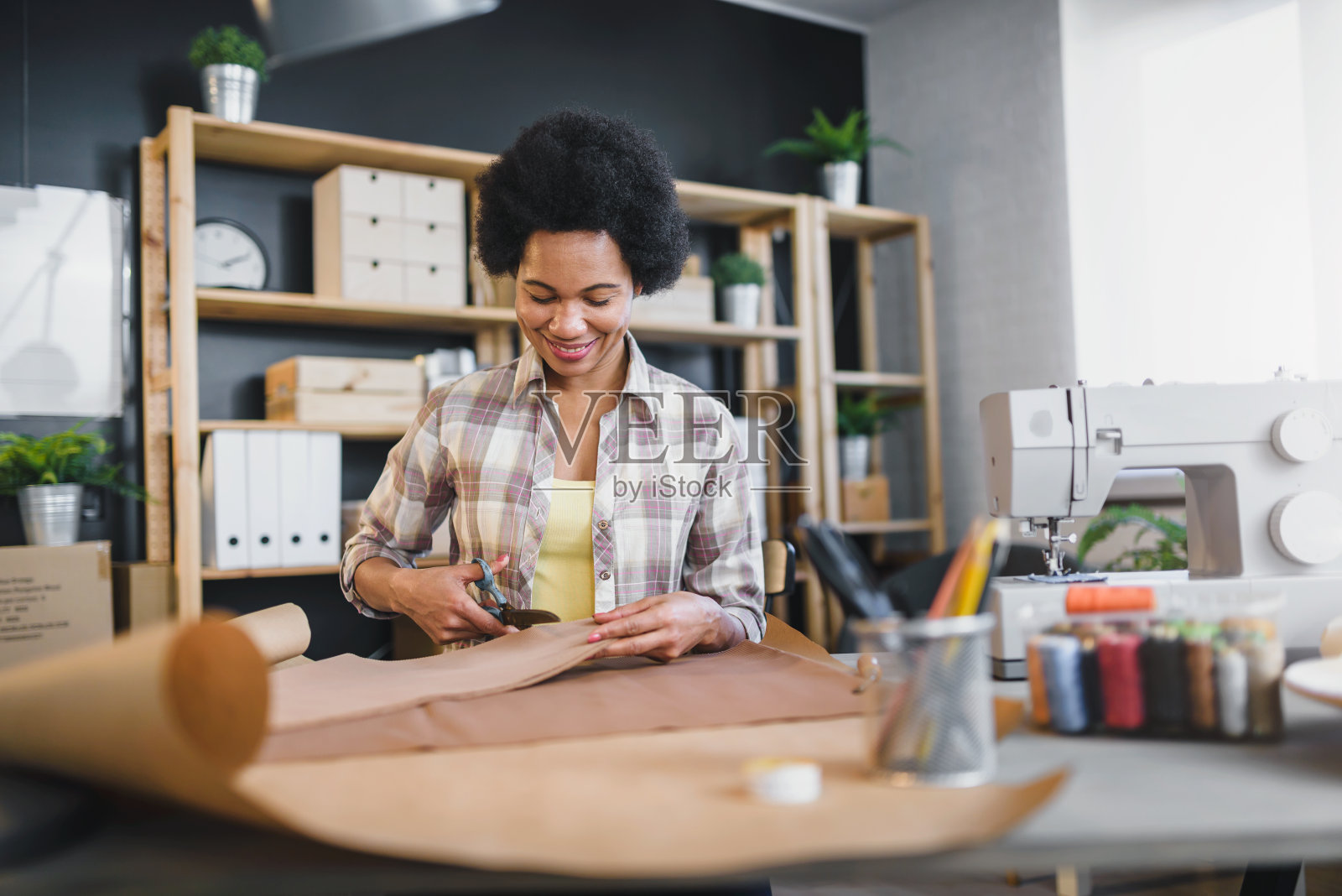 年轻的黑人女企业家在她的工作室工作。女裁缝。照片摄影图片