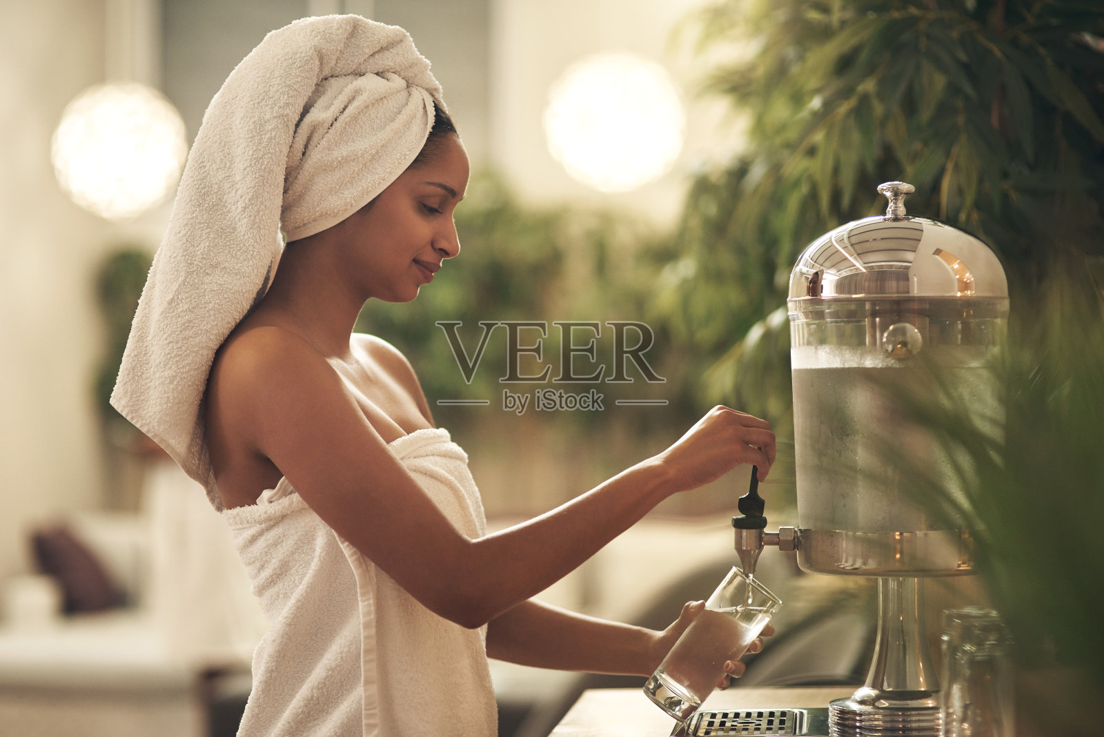 一个女人在一个日间水疗中心往饮水机里倒水的照片照片摄影图片