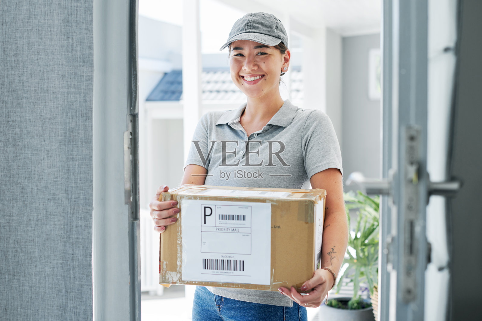 一个漂亮的年轻女子站在顾客家里送一个盒子照片摄影图片