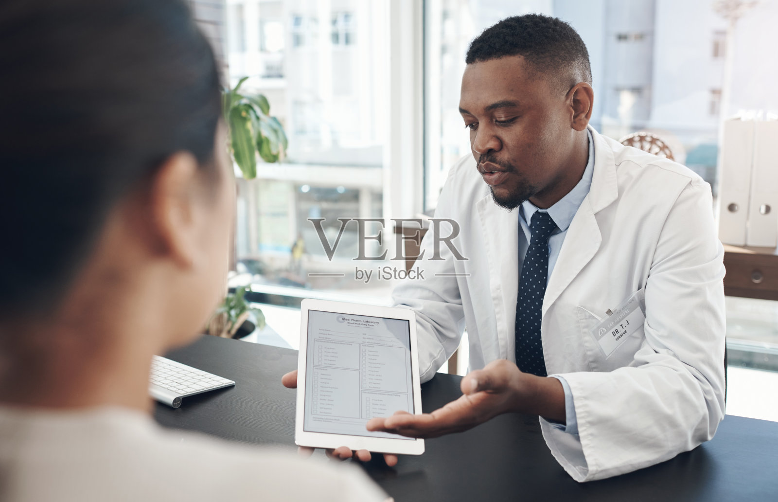 一名年轻男医生在办公室里与病人讨论一项调查照片摄影图片