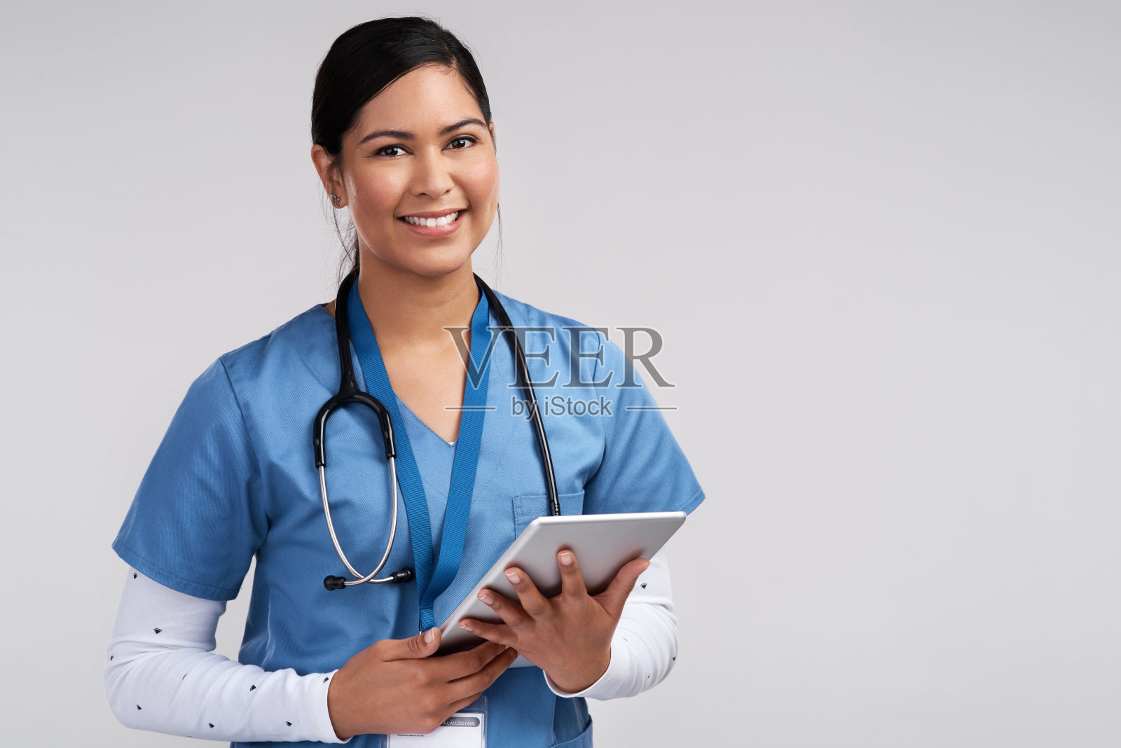 一名年轻医生使用平板电脑，戴着听诊器，背景是白色照片摄影图片