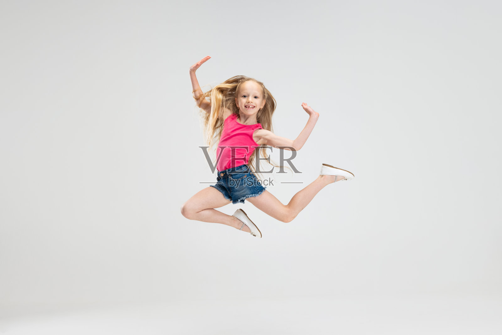 美丽的小女孩在休闲衣服跳孤立的白色工作室背景。快乐的童年的概念。照片摄影图片