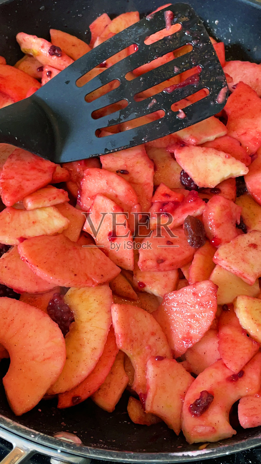 苹果片和黑莓在厨房铁架上用不粘锅、塑料铲、高架视图烹饪照片摄影图片