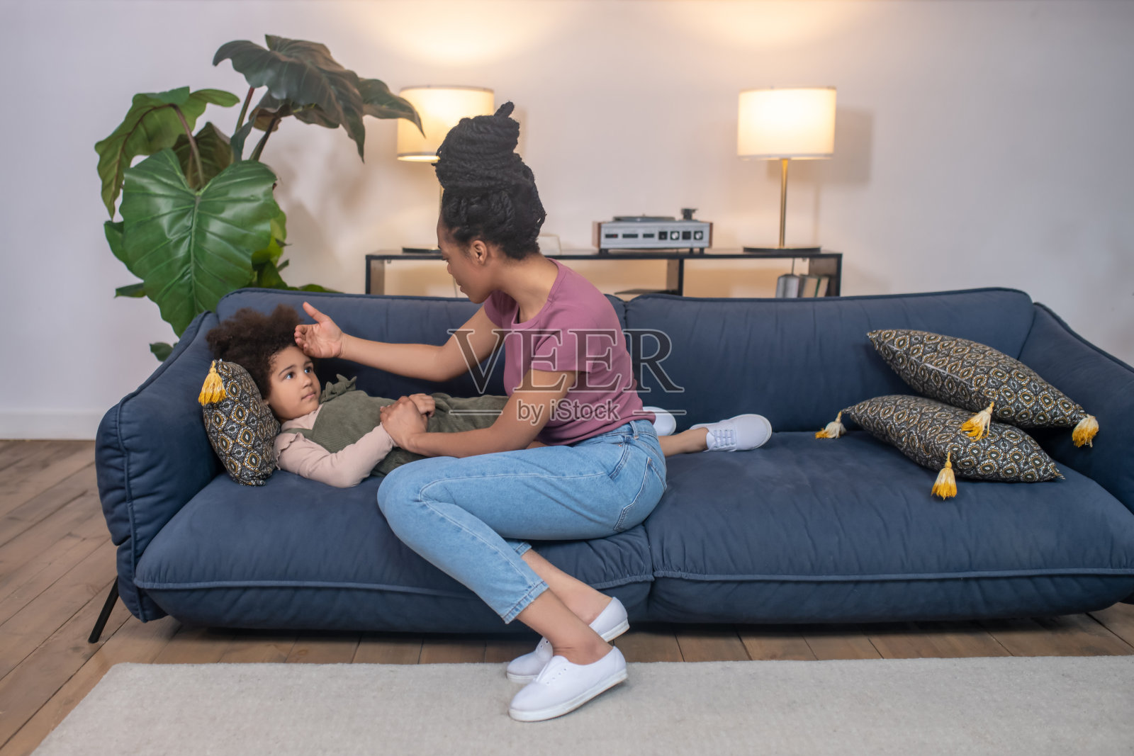 非裔美国妇女坐在疲惫的小女儿旁边照片摄影图片