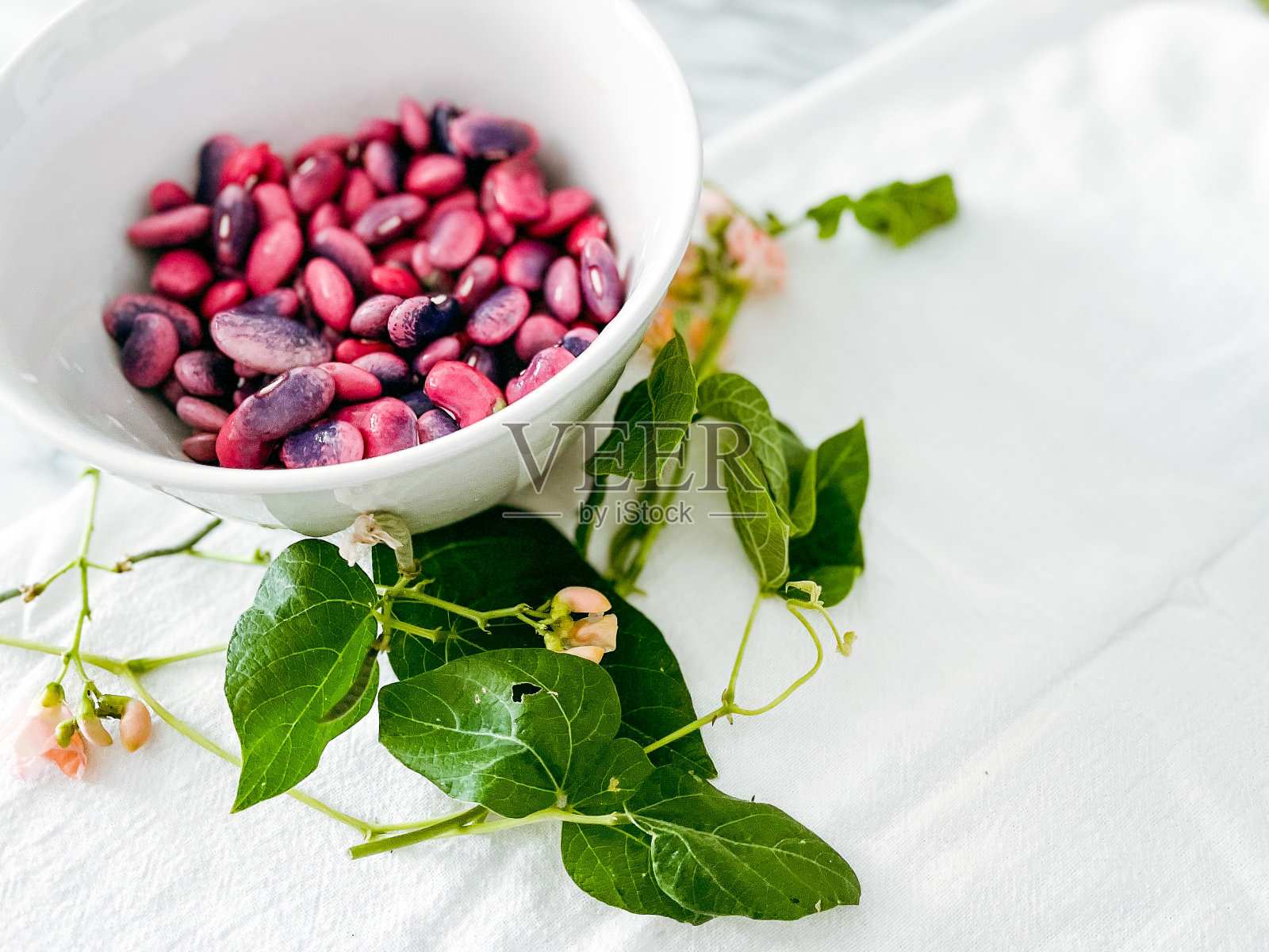 鲜红的菜豆在碗里，还有花和藤蔓照片摄影图片