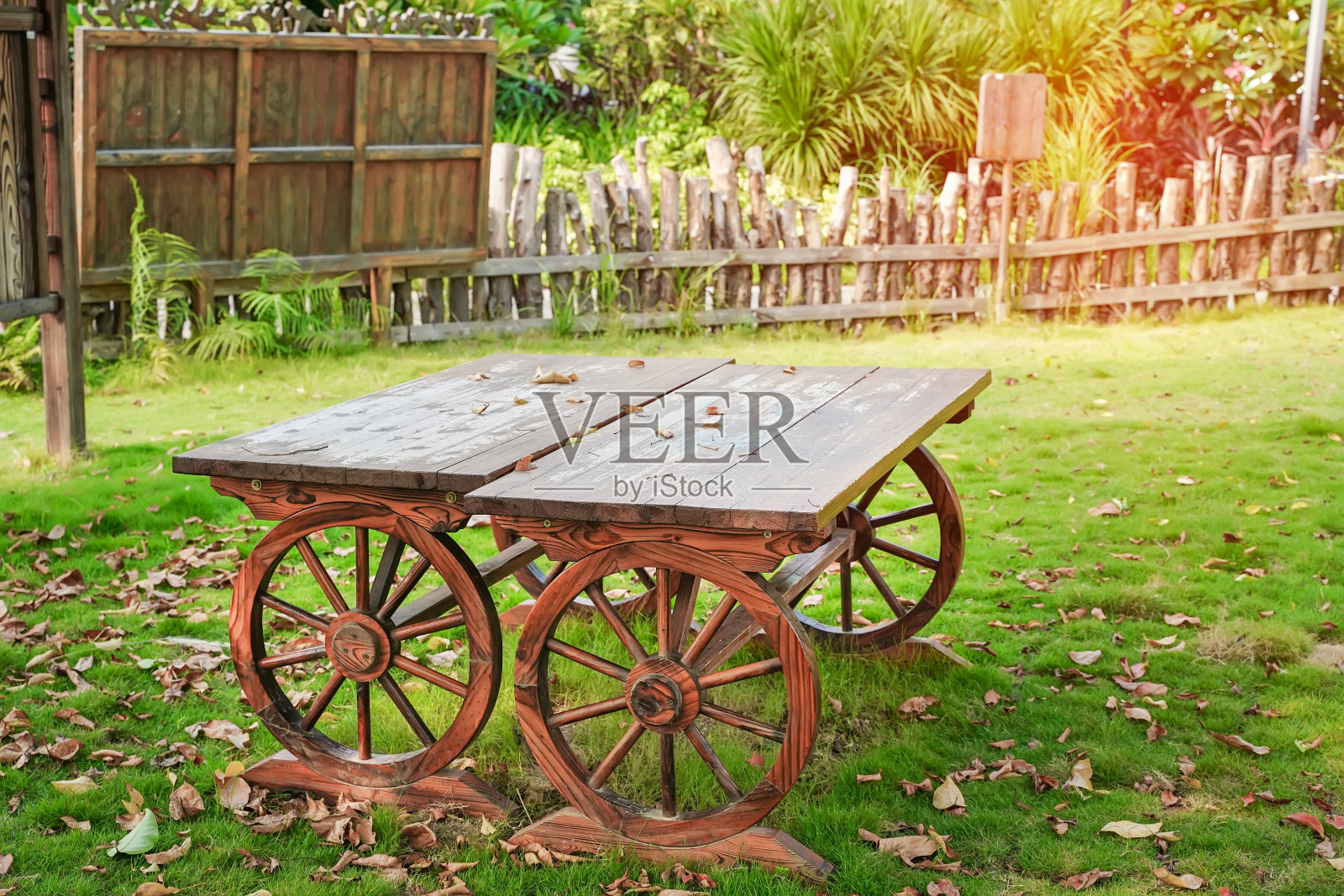 木推车桌子与四个木轮子在花园里。老式的车。照片摄影图片