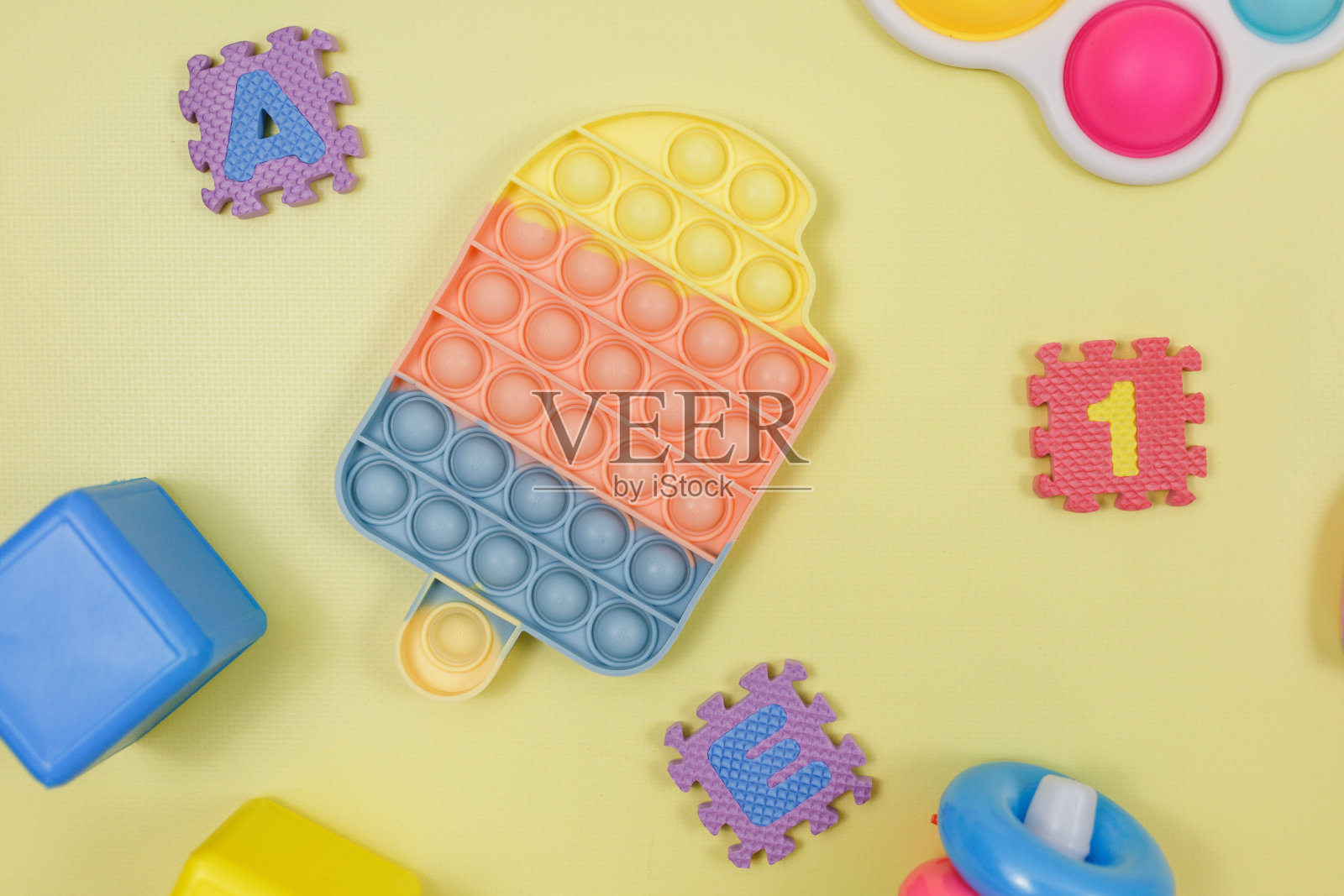 流行的硅胶抗应力pop-it玩具为一个孩子在黄色紫罗兰绿色的背景。时尚的缓解压力感官烦躁玩具。有趣的泡泡多色小玩意为成人和儿童照片摄影图片