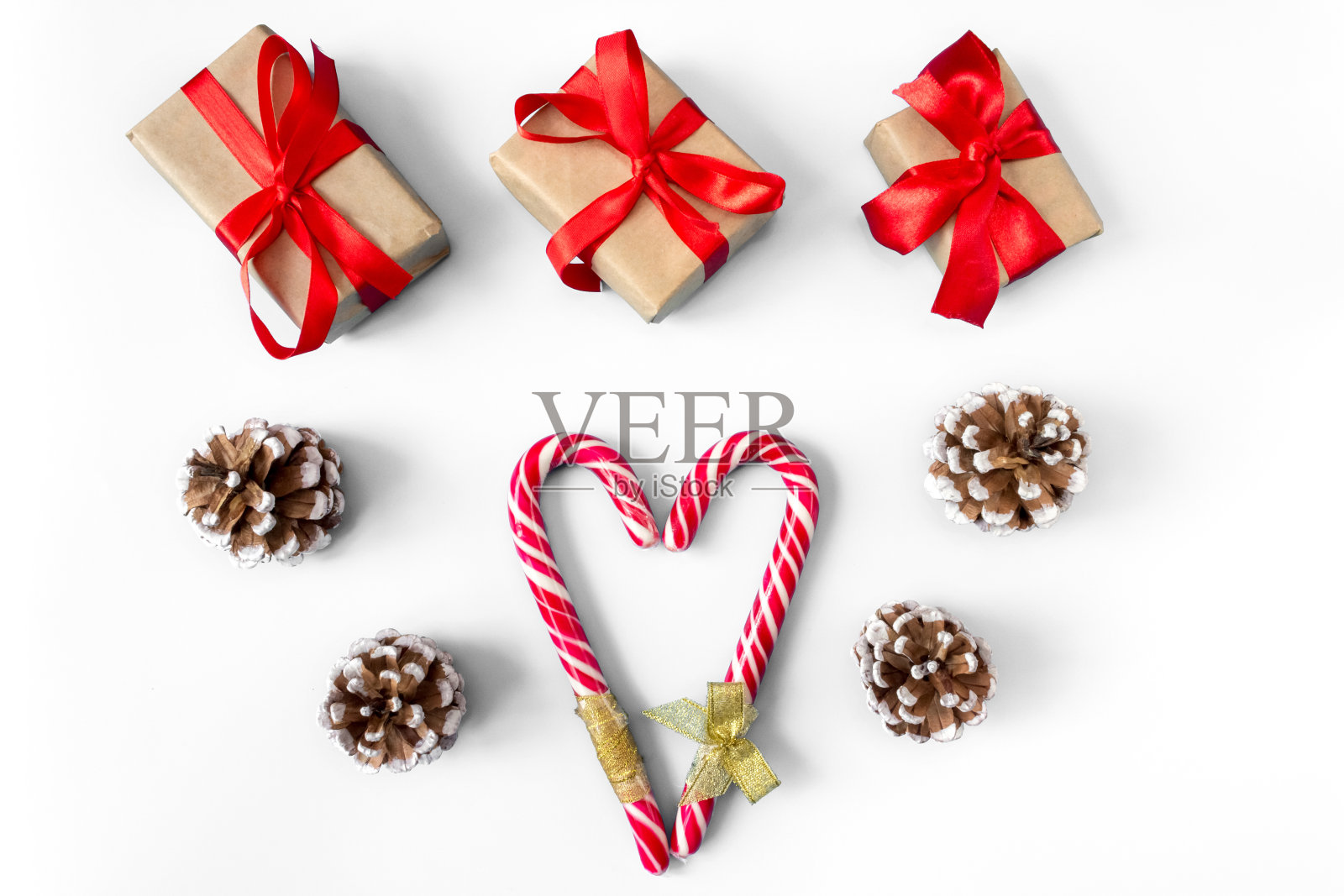 礼盒松果和焦糖棒的形状的心在白色的背景。照片摄影图片