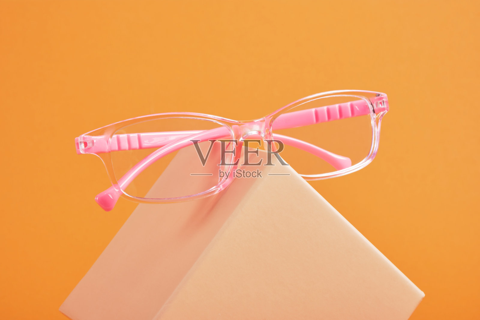 米色礼品盒上的粉红色儿童眼镜，棕色背景，复制空间，光学商店的折扣和促销照片摄影图片