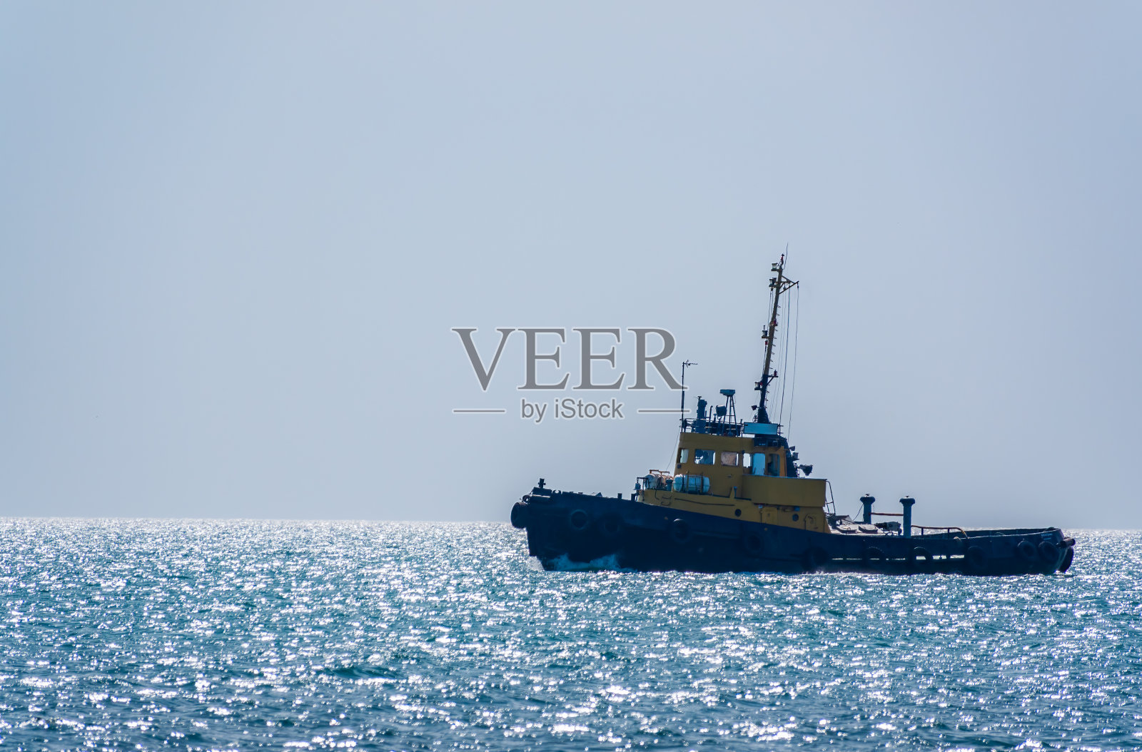 那艘拖船在蓝色的海上航行。照片摄影图片