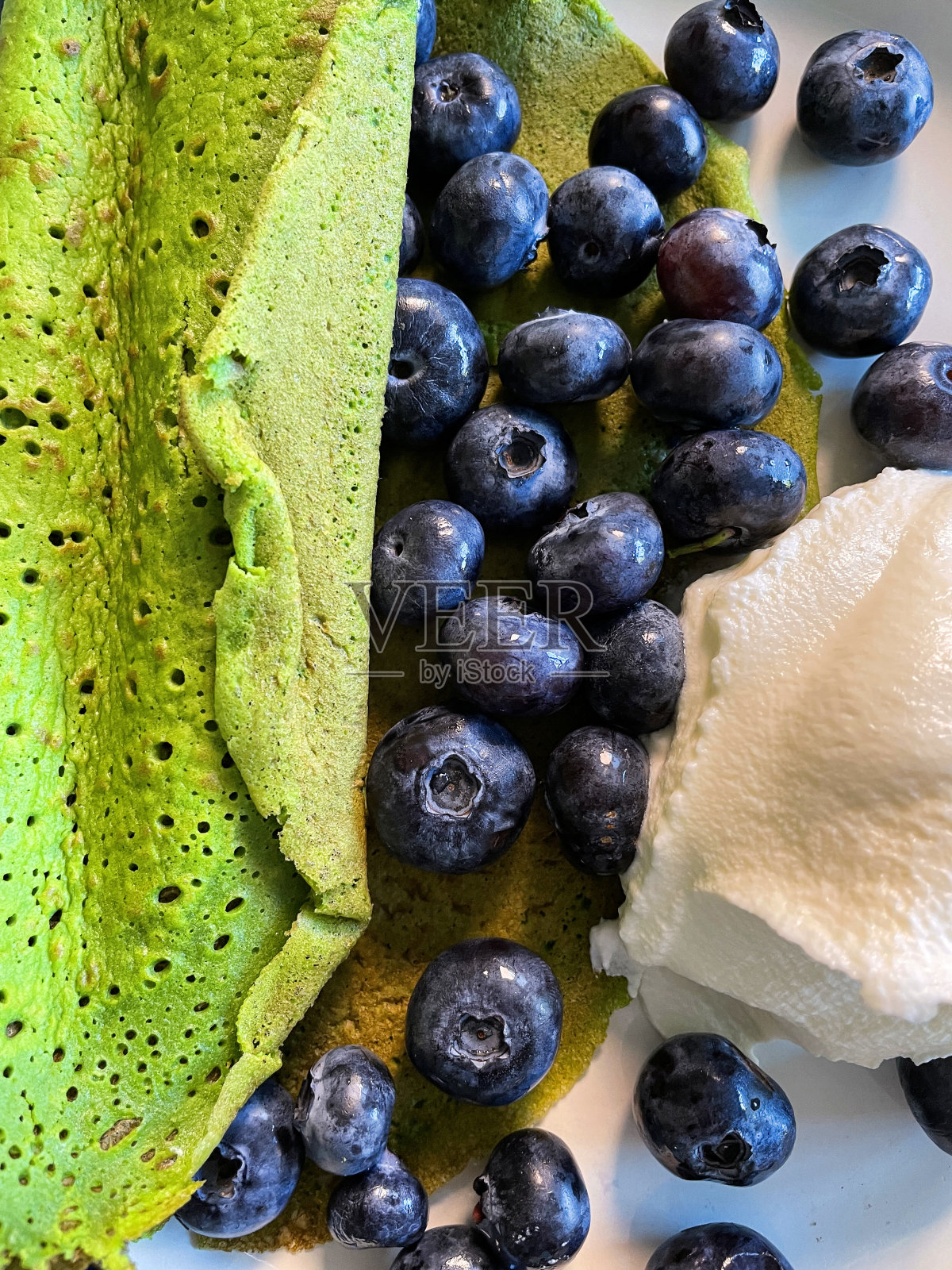 全框自制的绿色菠菜煎饼配上新鲜的蓝莓和一团希腊酸奶，更健康的早餐概念，高观感照片摄影图片