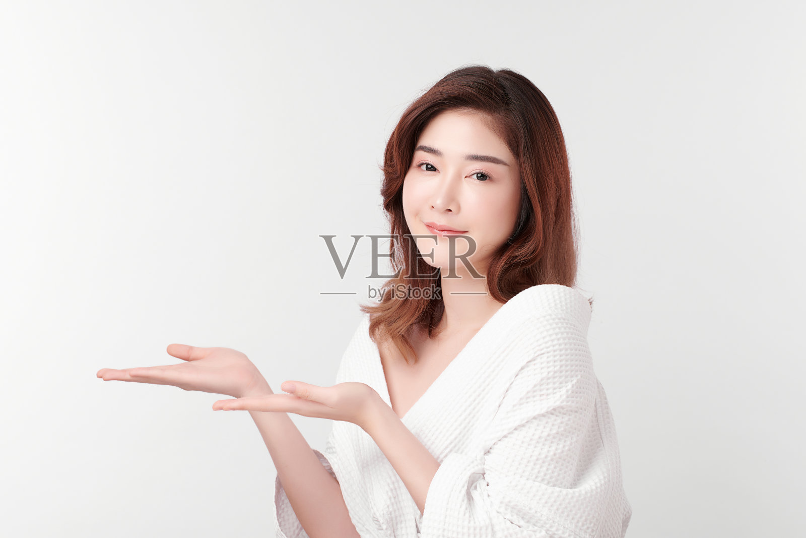 美丽年轻的亚洲女人穿着浴衣在白色的背景，面部护理，面部治疗，美容，美容和水疗概念。照片摄影图片