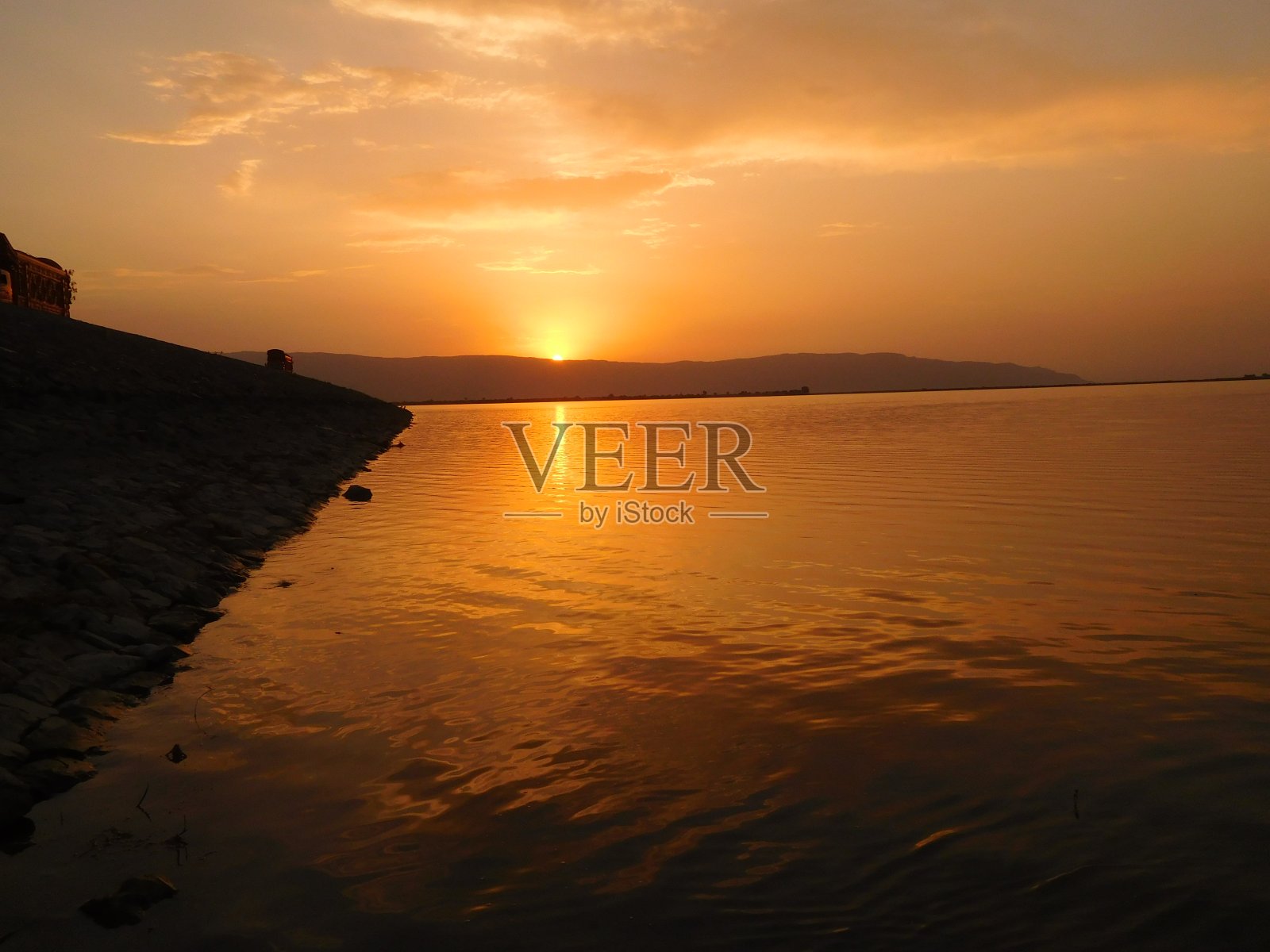 美丽的暗橙色日落地平线，天空，太阳，山，云，水波和涟漪照片摄影图片