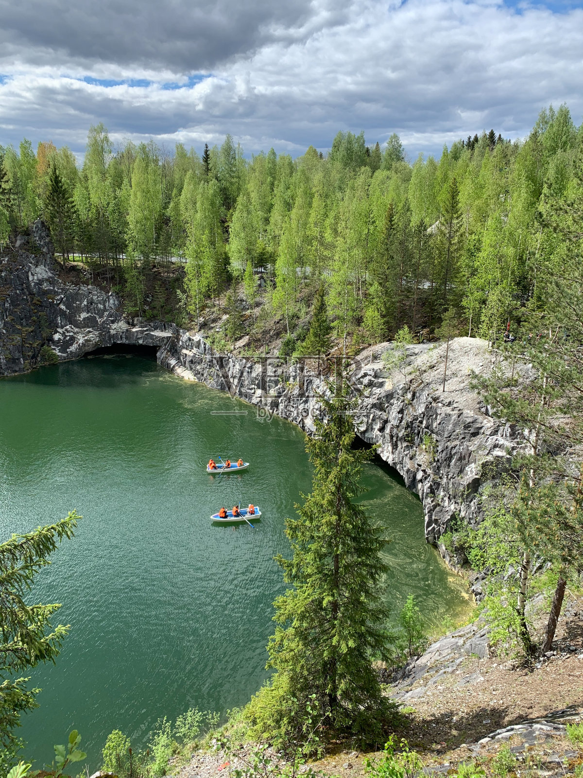 山顶的悬崖，洞穴和船漂浮在大理石峡谷碧绿的水在Ruskeala山公园在夏天的一天。照片摄影图片