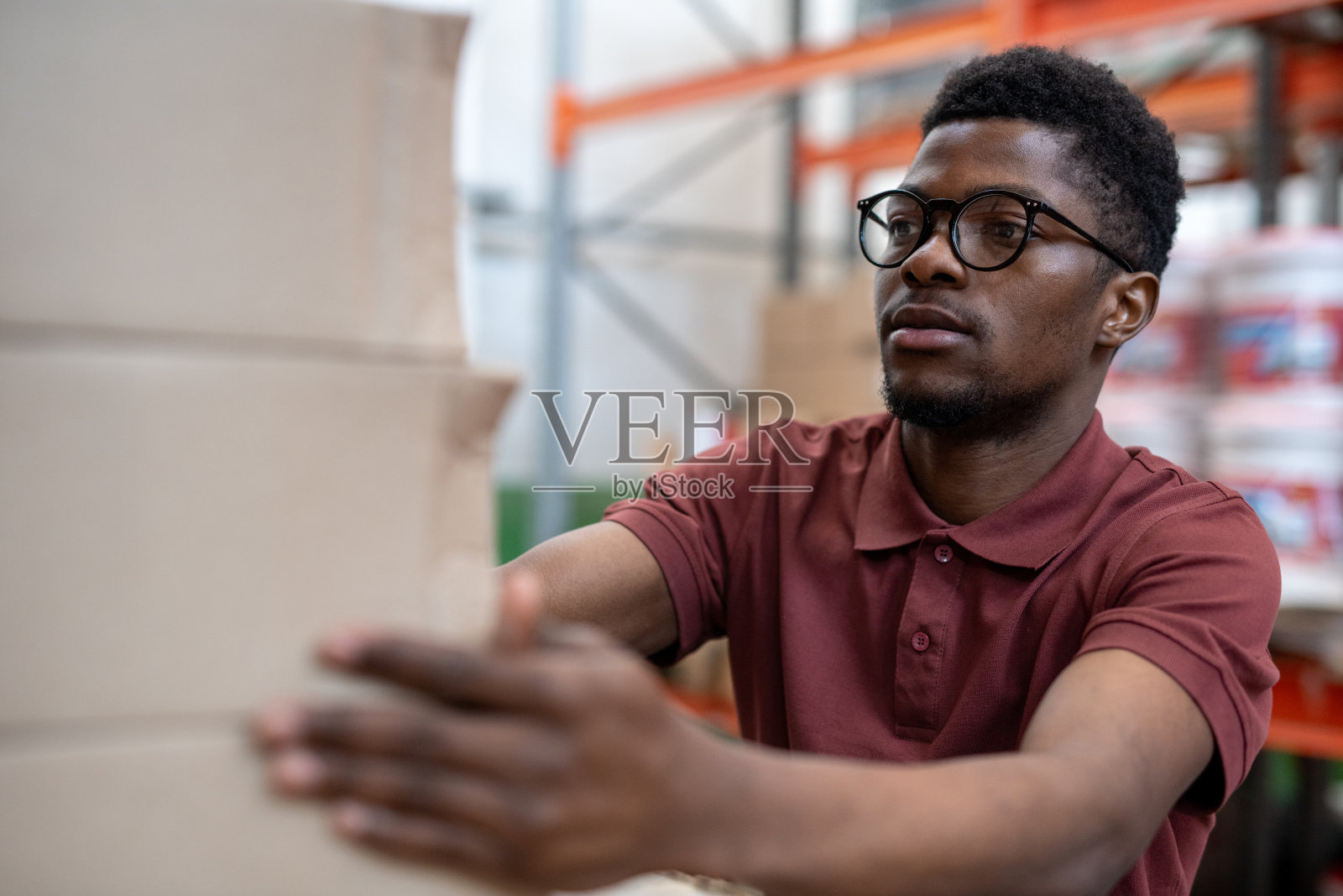 年轻的男性装载机把纸板箱堆在一起照片摄影图片