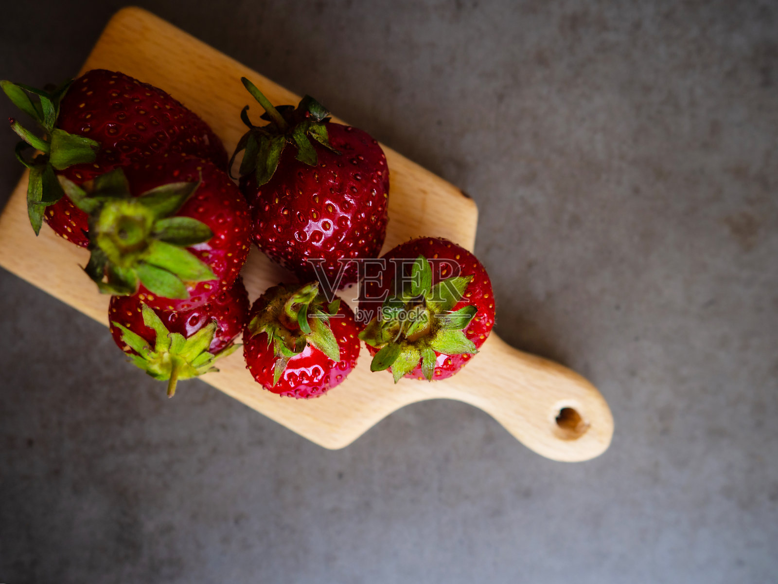 新鲜、成熟的草莓放在一块木板上和一张灰色的混凝土桌子上。贝瑞。背景和纹理。照片摄影图片