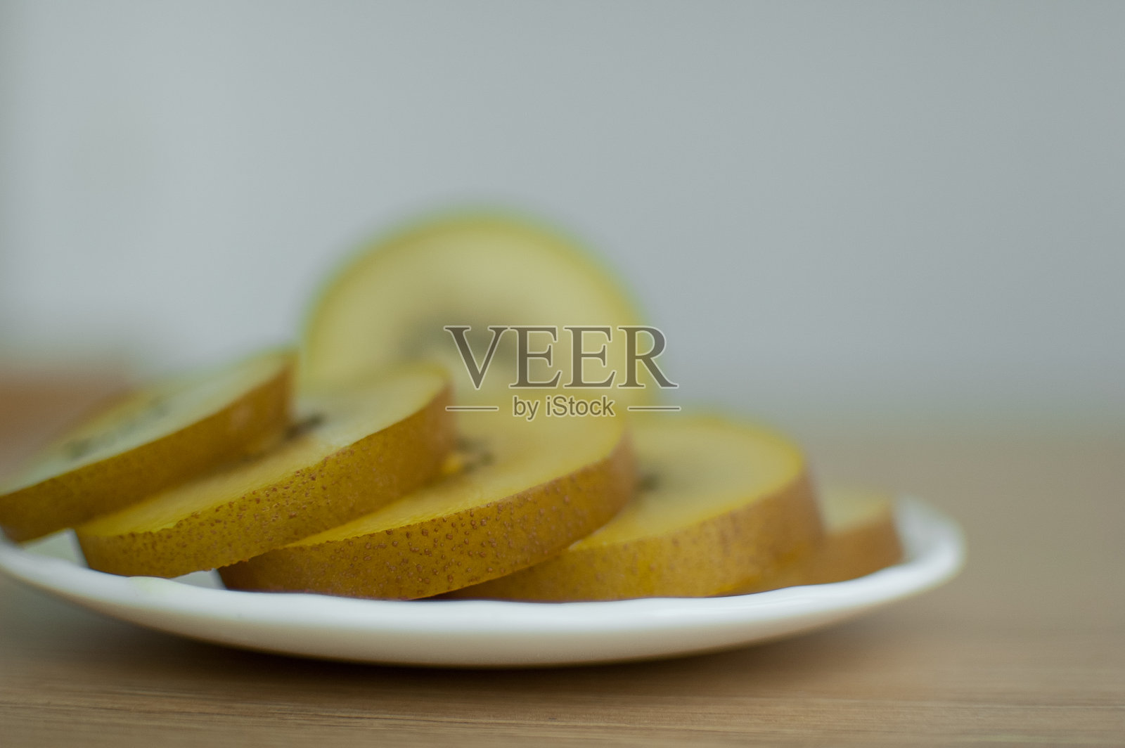 厨房的白色盘子上放着金黄色果肉的几片猕猴桃。异域水果，健康饮食理念照片摄影图片