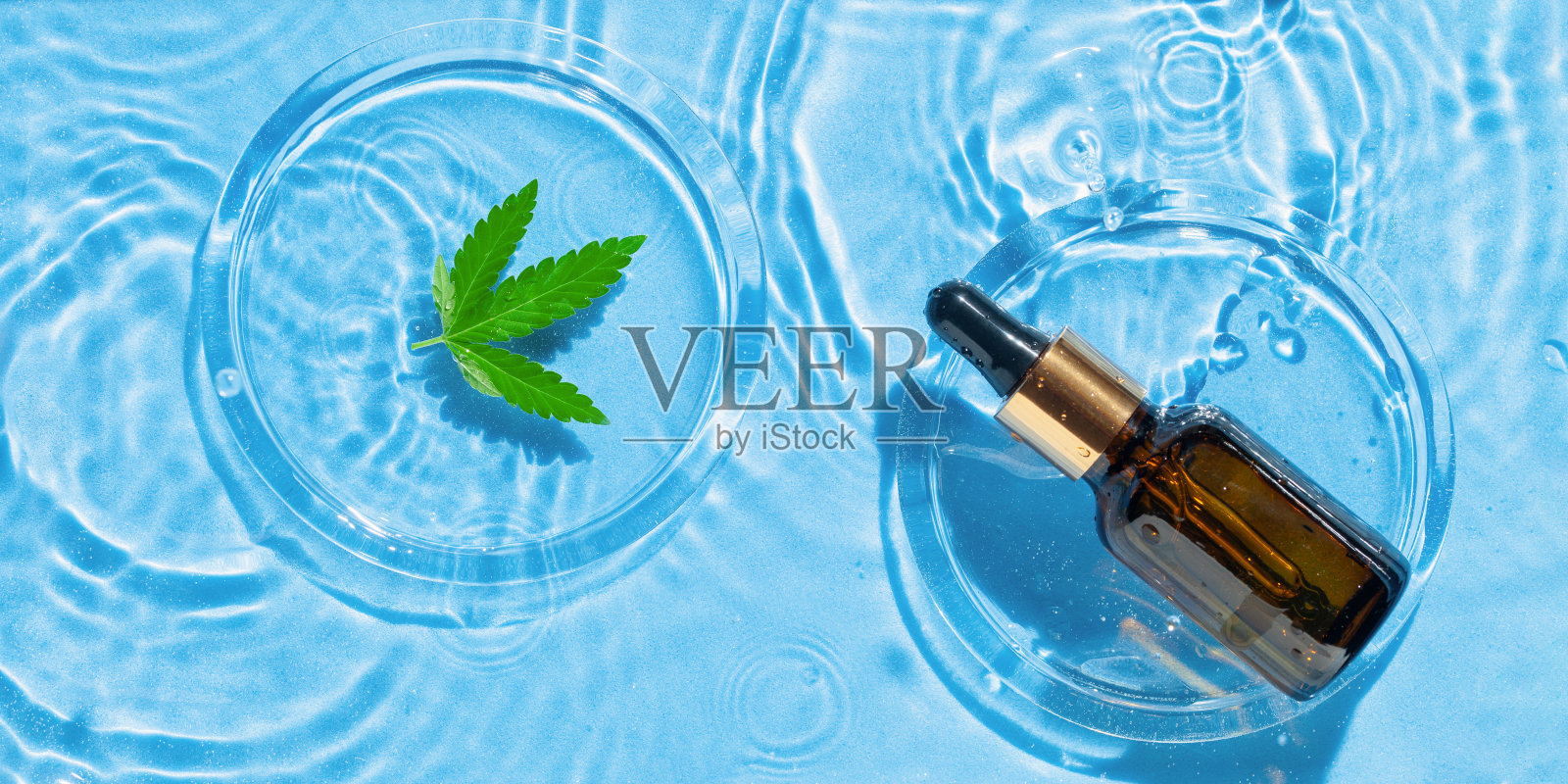 化妆品spa医疗皮肤护理，血清瓶，胶束爽肤水或乳液和麻叶蓝色水纹理背景与飞溅。平的。前视图。强光照片摄影图片