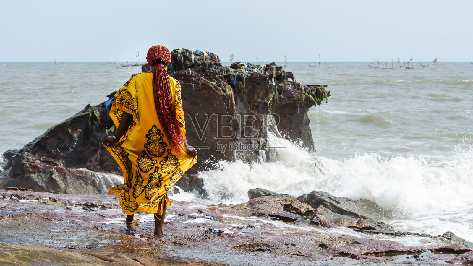 一名非洲妇女在加纳阿克拉海滩的岩石上行走照片摄影图片