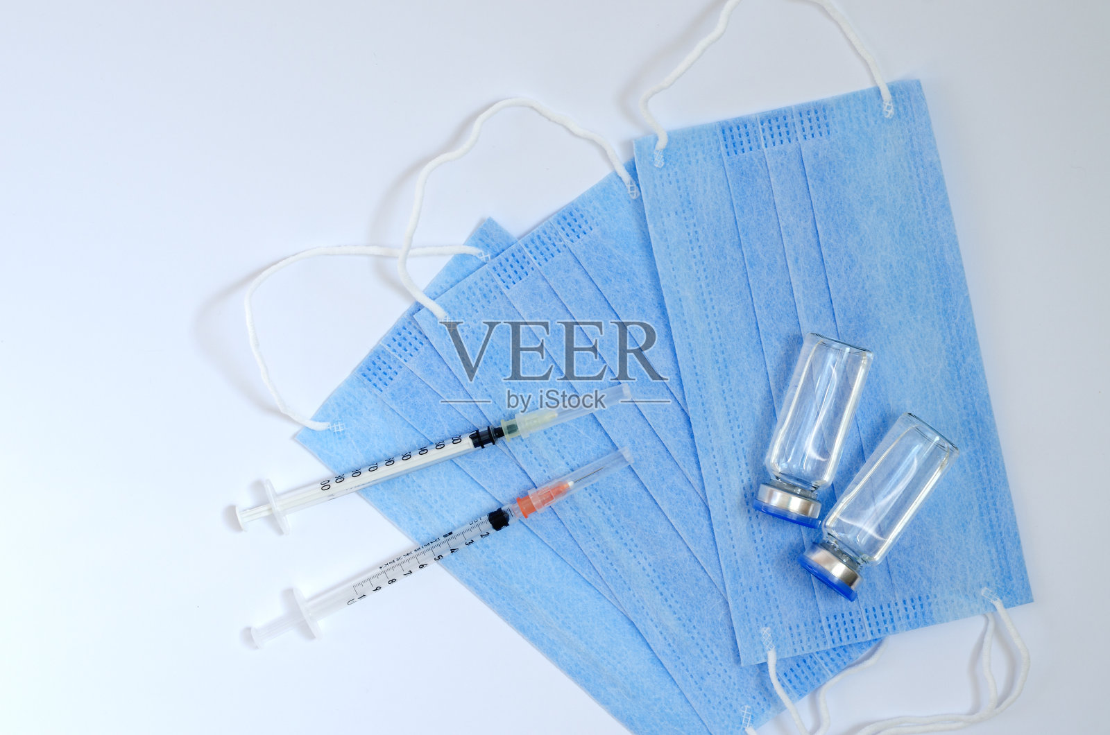 创意糖尿病概念。胰岛素注射。与过敏。冠状病毒病疫苗接种用医用口罩和疫苗玻璃瓶俯视图照片摄影图片