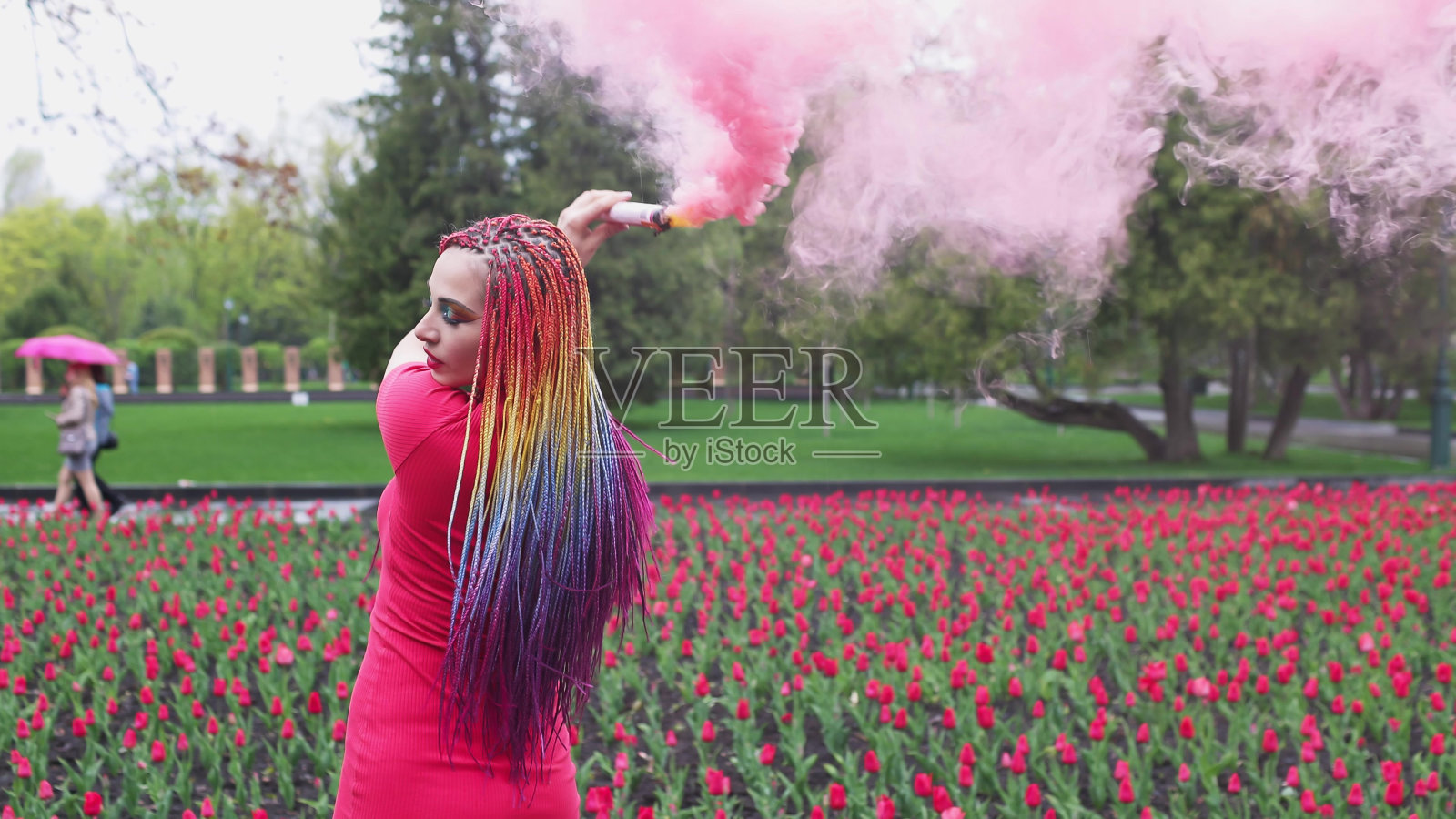 一个女孩带着彩虹辫，穿着红裙子摆姿势照片摄影图片