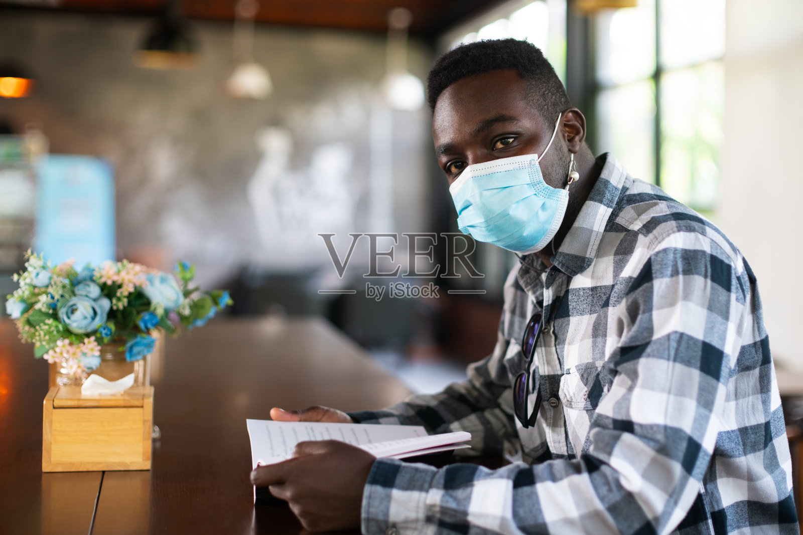 非洲人戴着口罩在咖啡馆看书照片摄影图片