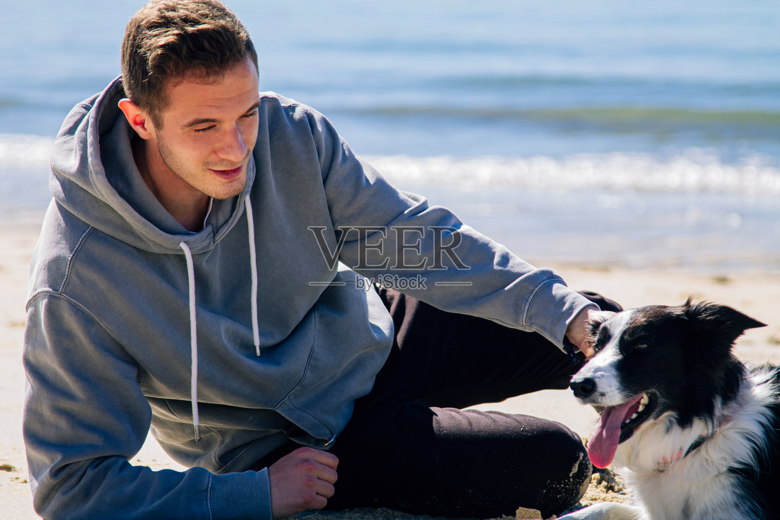 一个年轻人和他的狗在海滩上的肖像照片摄影图片
