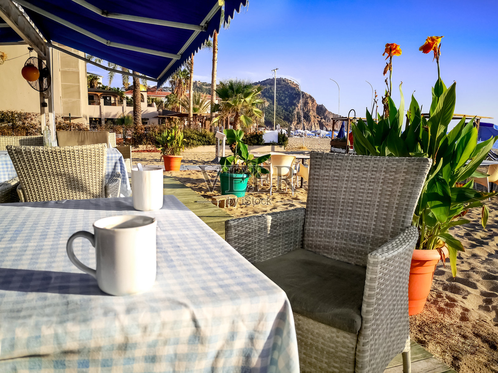 土耳其阿兰亚的一家海滩咖啡馆里，两个白色杯子放在铺着格子桌布和柳条椅的桌子上。照片摄影图片