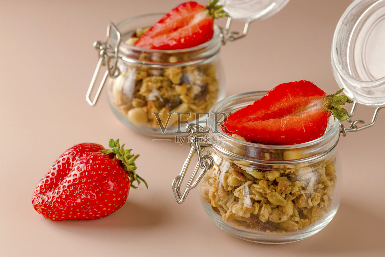 格兰诺拉麦片，健康食品，甜点，小吃。保持健康的早餐。鲜果和草莓的什锦麦片在粉红色的背景上。饮食的概念。素食照片摄影图片