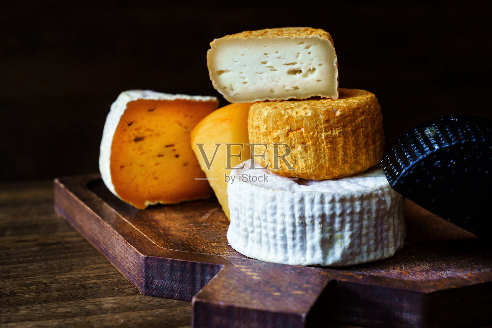 木桌上的切菜板上放着各式各样的奶酪头。奶酪工厂。照片摄影图片